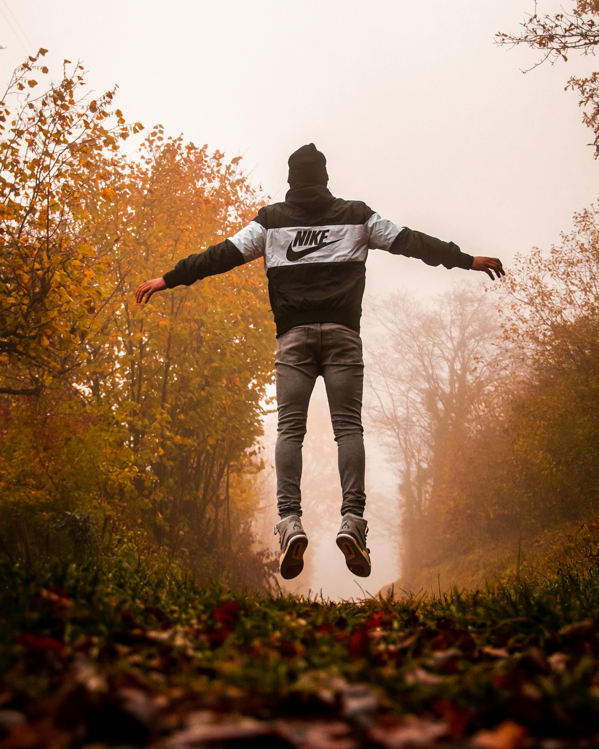 A man in a Nike hoodie and gray pants jumping in the air | Source: Pexels