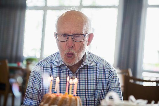 Photo of an elderly man  blowing out birthday candles | Photo: Getty Images