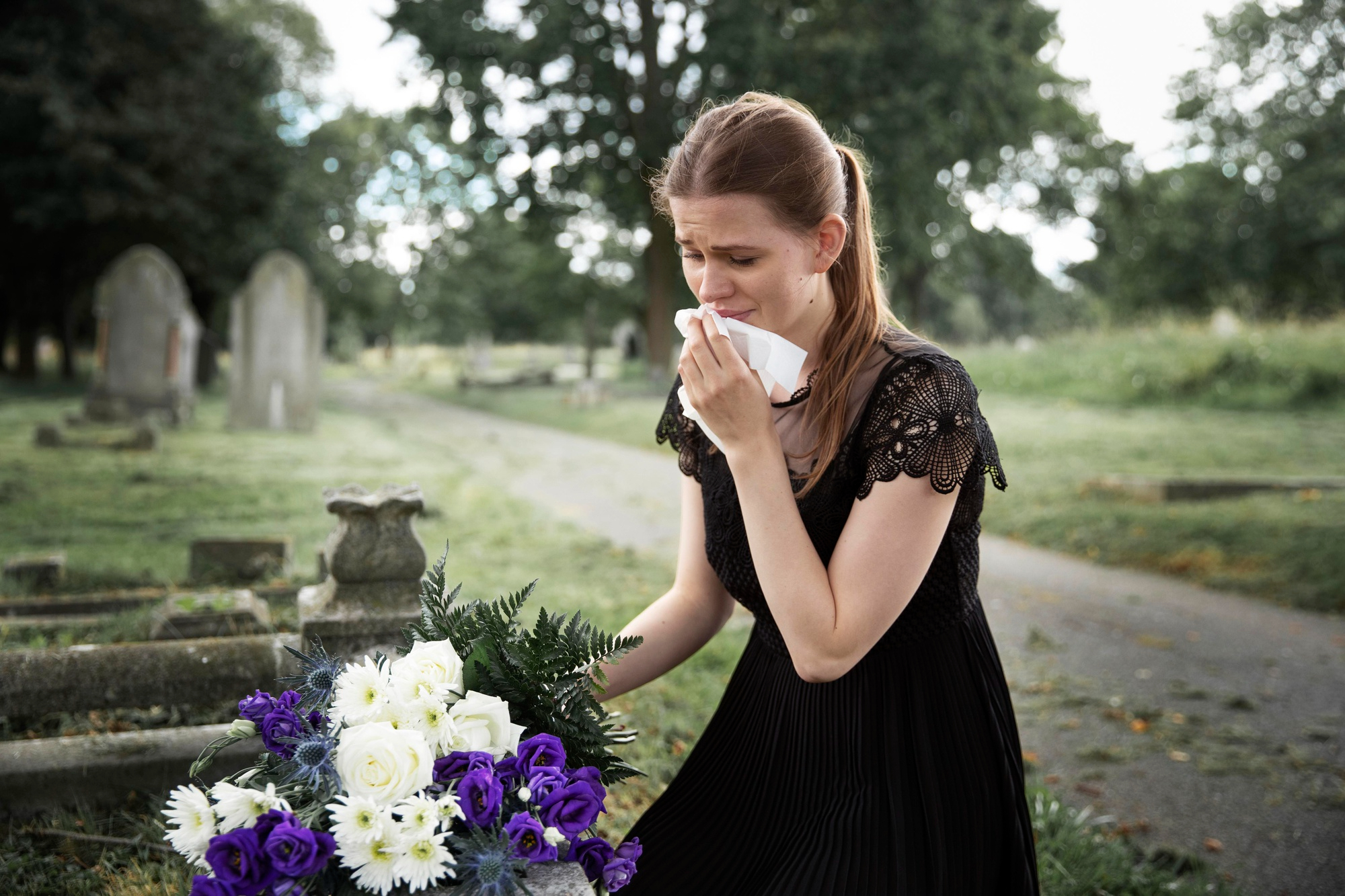 A young woman crying while visiting a loved one's grave | Source: Freepik