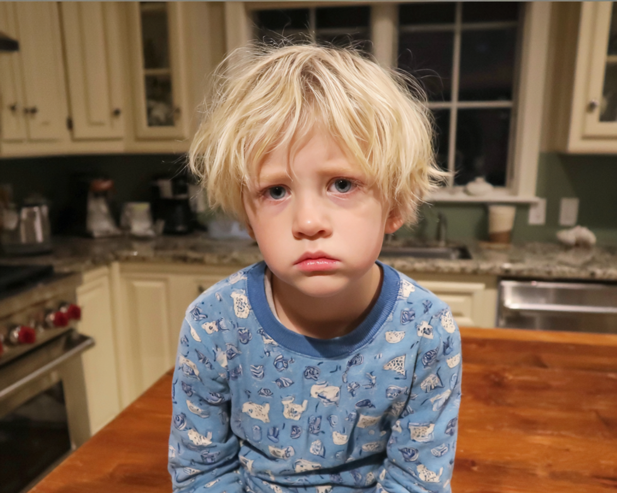 A sad little boy sitting in a kitchen | Source: Midjourney
