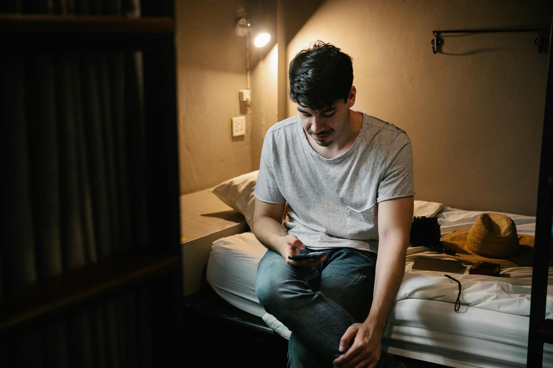 A man sitting on the bed and using his phone | Source: Pexels