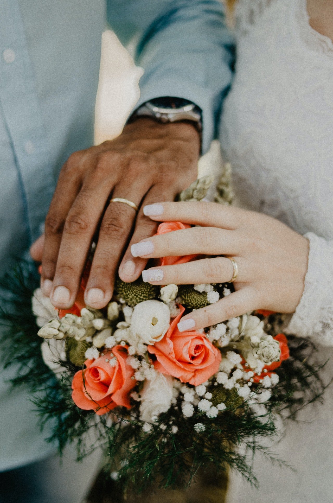 Man and woman's hands on top of flower bouquet | Source: Pexels