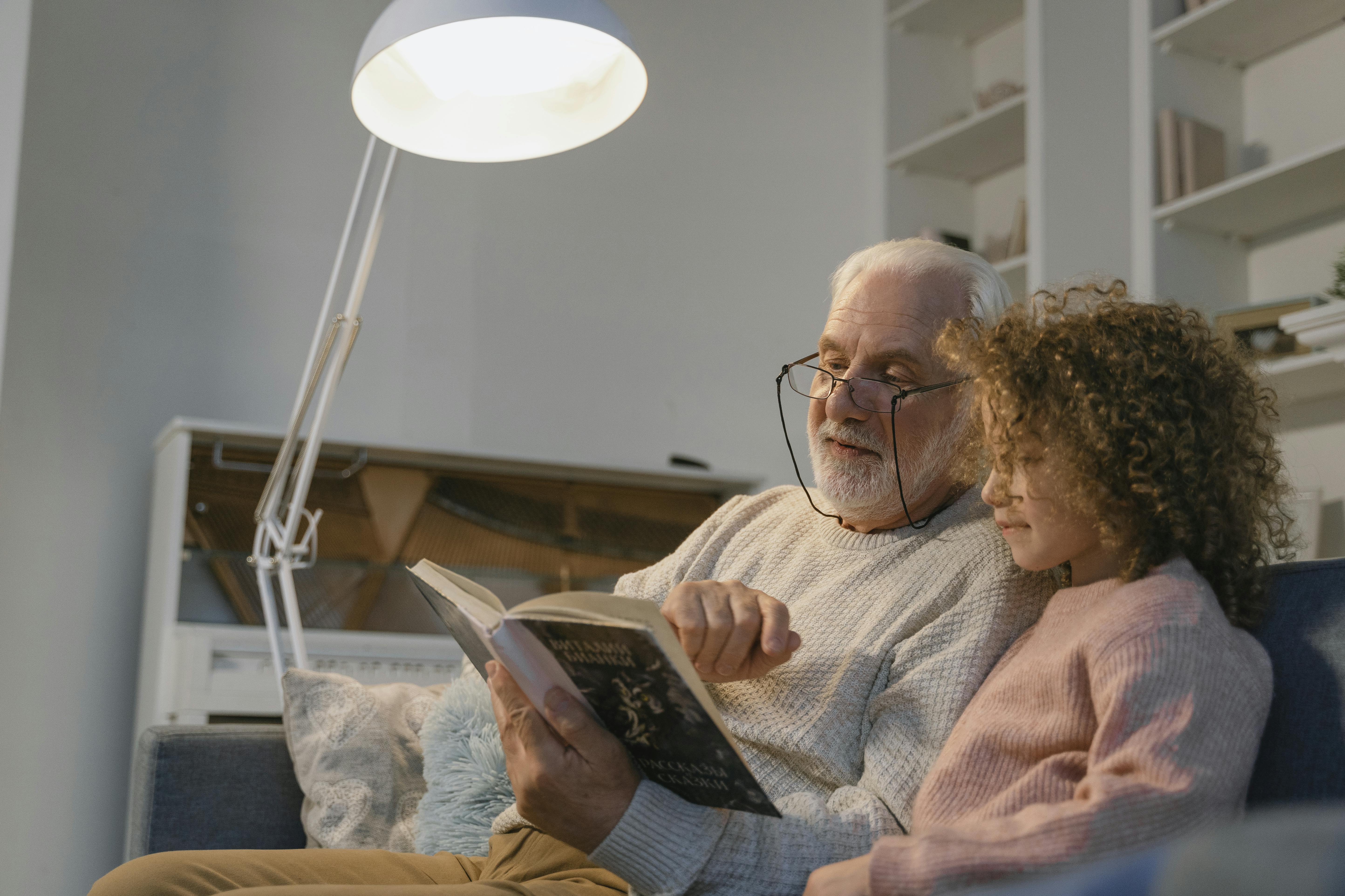 A grand father reading a book to his granddaughter | Source: Pexels