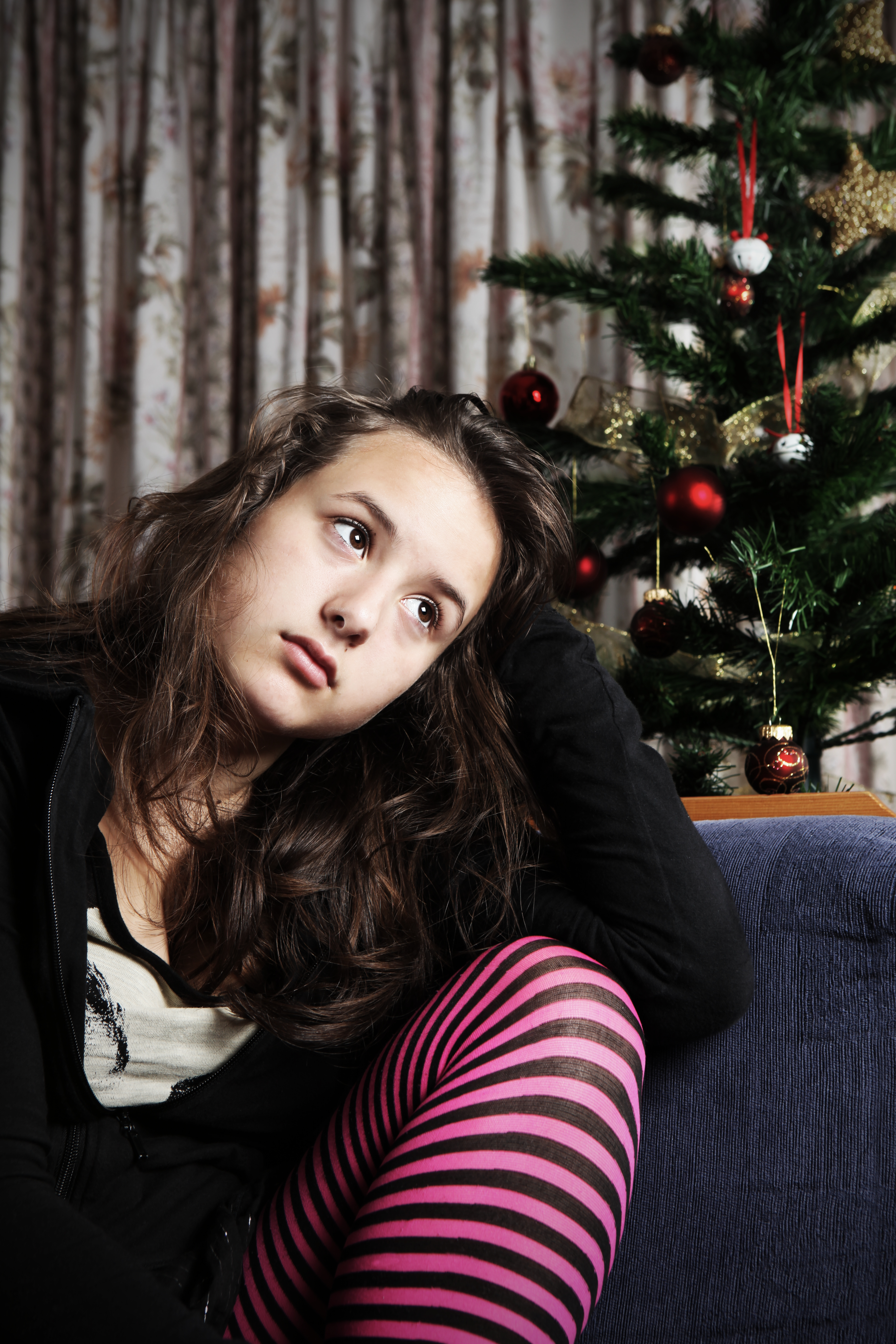 A sad teenage girl sitting next to a Christmas tree | Source: Getty Images