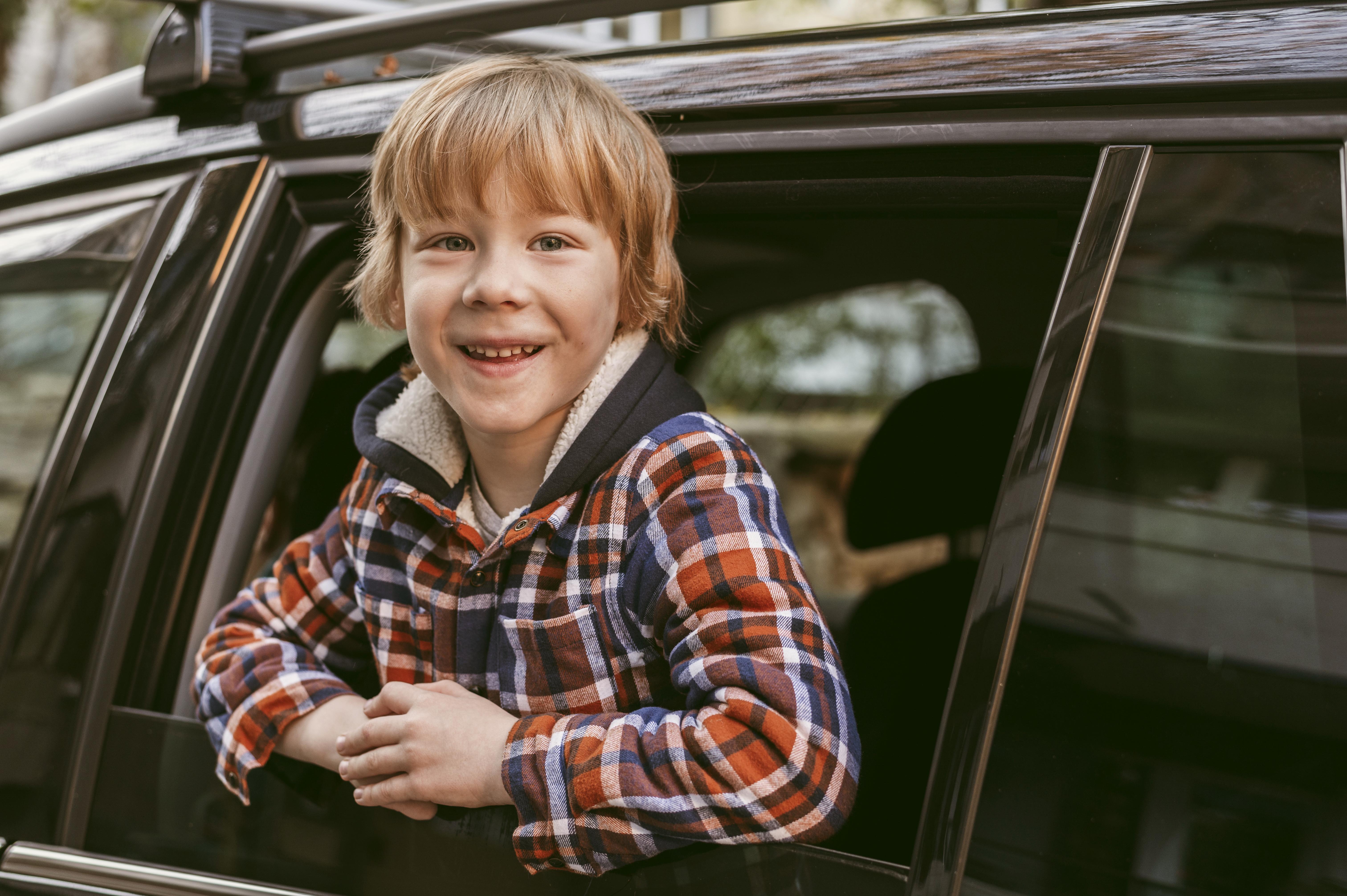 A happy boy in the backseat of a car | Source: Freepik