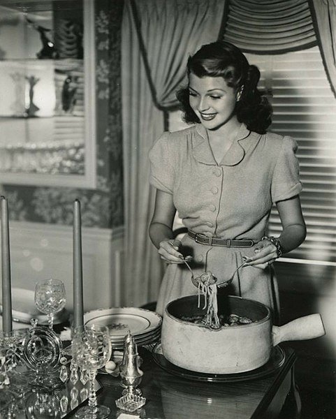 Rita Hayworth serves up spaghetti. In You'll Never Get Rich, 1941. | Source: Wikimedia Commons