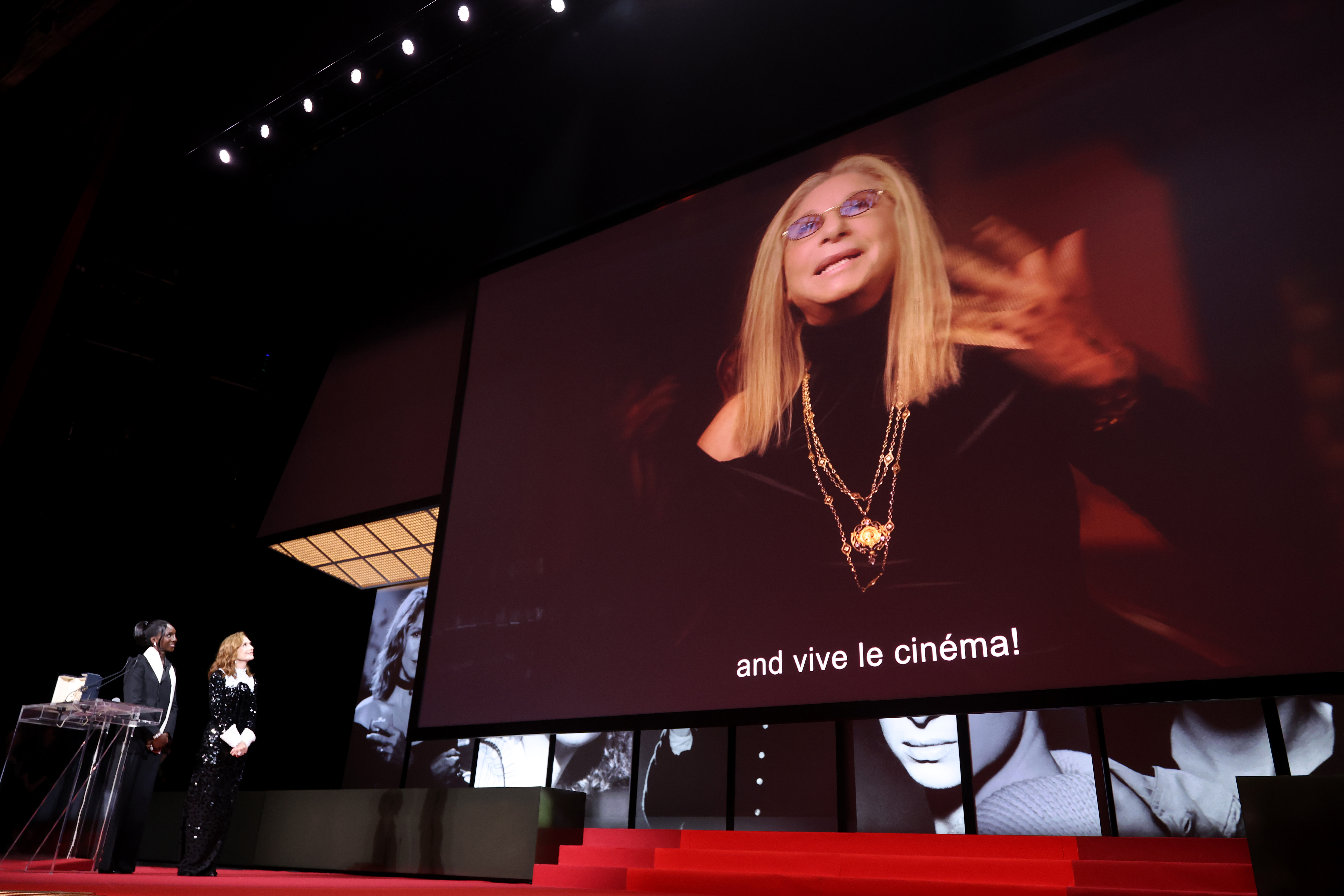 Barbra Streisand's pre-recorded speech plays after Isabelle Huppert accepted the Honorary Palme d'Or on her behalf from host Eye Haïdara on stage during the closing ceremony of the 79th annual Cannes Film Festival at Palais des Festivals on May 23, 2026 in France. | Source: Getty Images