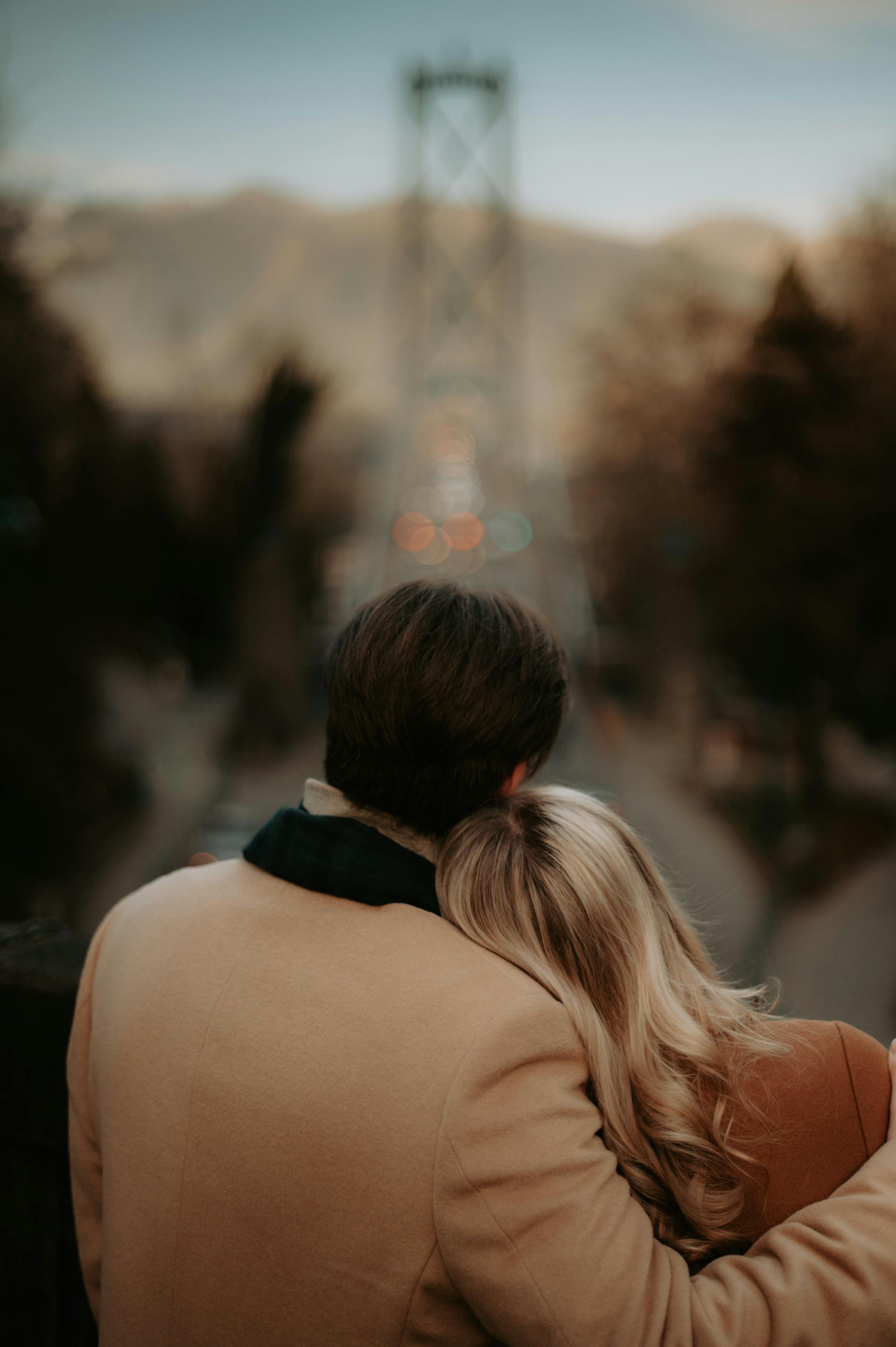 A man embracing a woman against a blurred cityscape | Source: Pexels