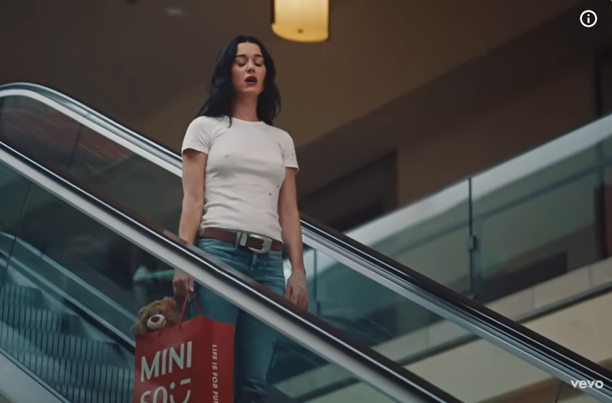 Katy Perry stands on a moving escalator, as seen in her music video "Bandaids," dated November 7, 2025. | Source: Youtube/KatyPerry