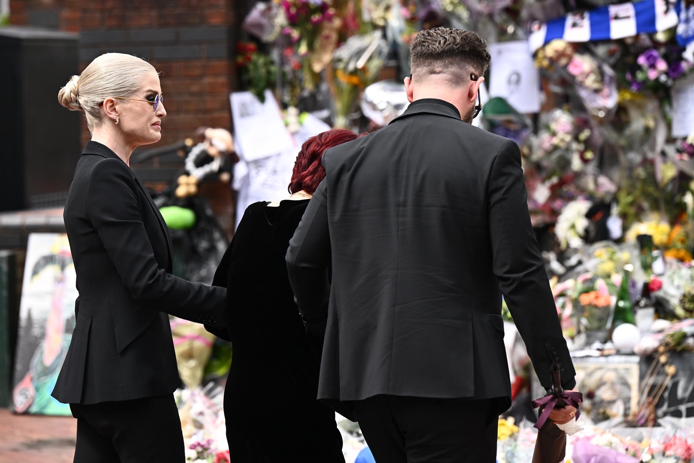 Kelly and Jack help Sharon as they approach the fan tributes left for Ozzy at Black Sabbath Bridge in Birmingham, England on July 30, 2025. | Source: Getty Images