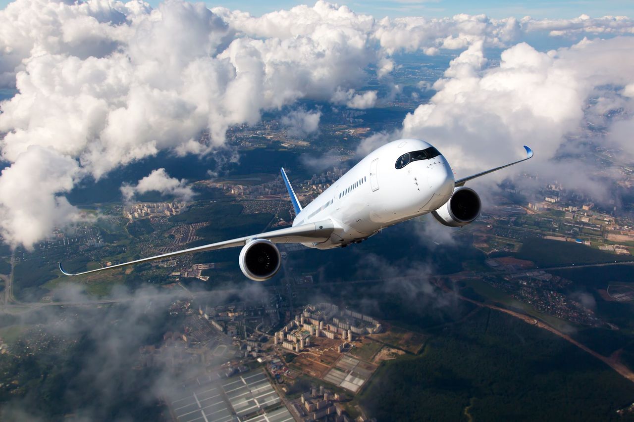 A passenger plane flying upwards above a city. | Photo: Shutterstock