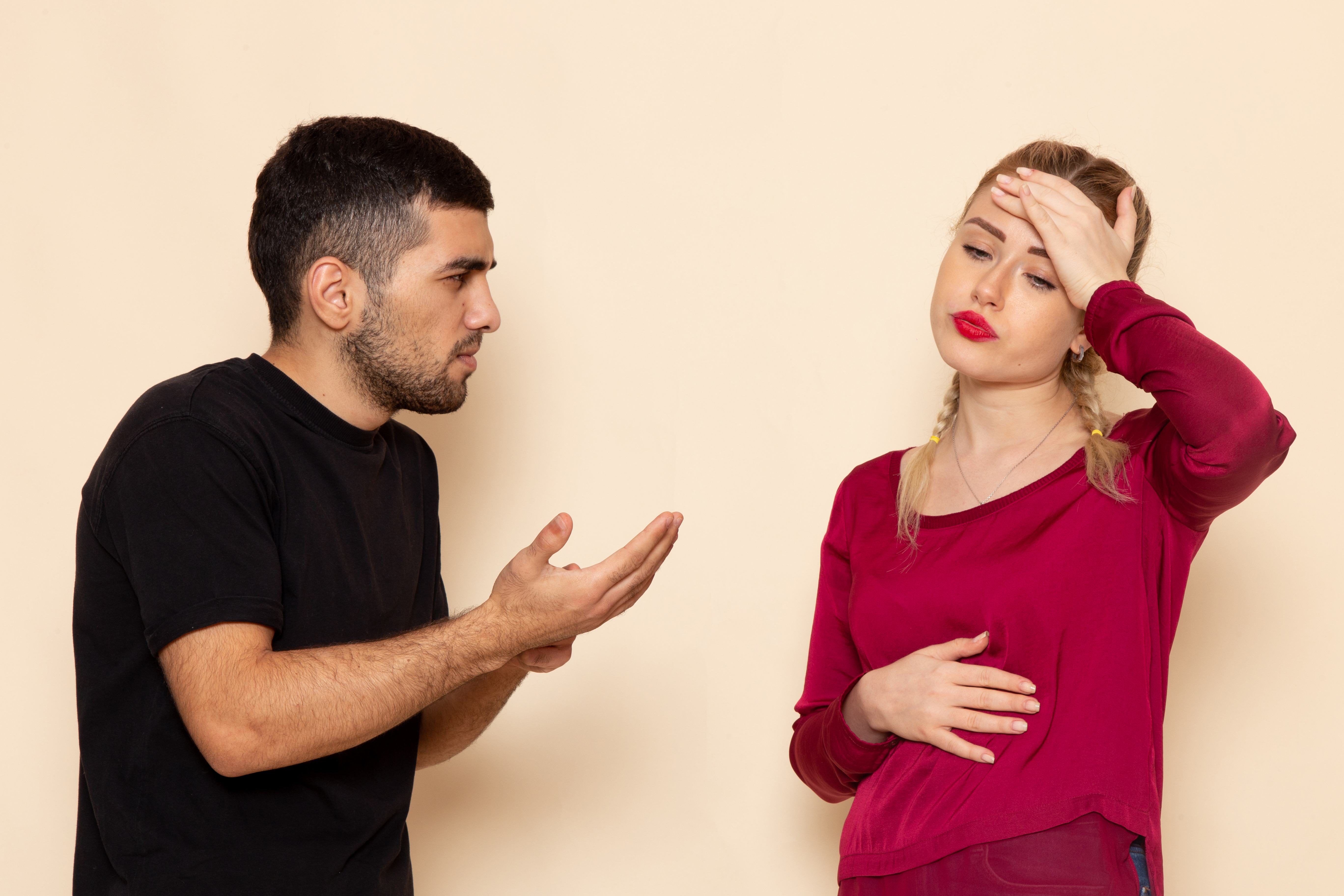 Man gesturing to a woman whose hand is on her forehead | Source: Freepik
