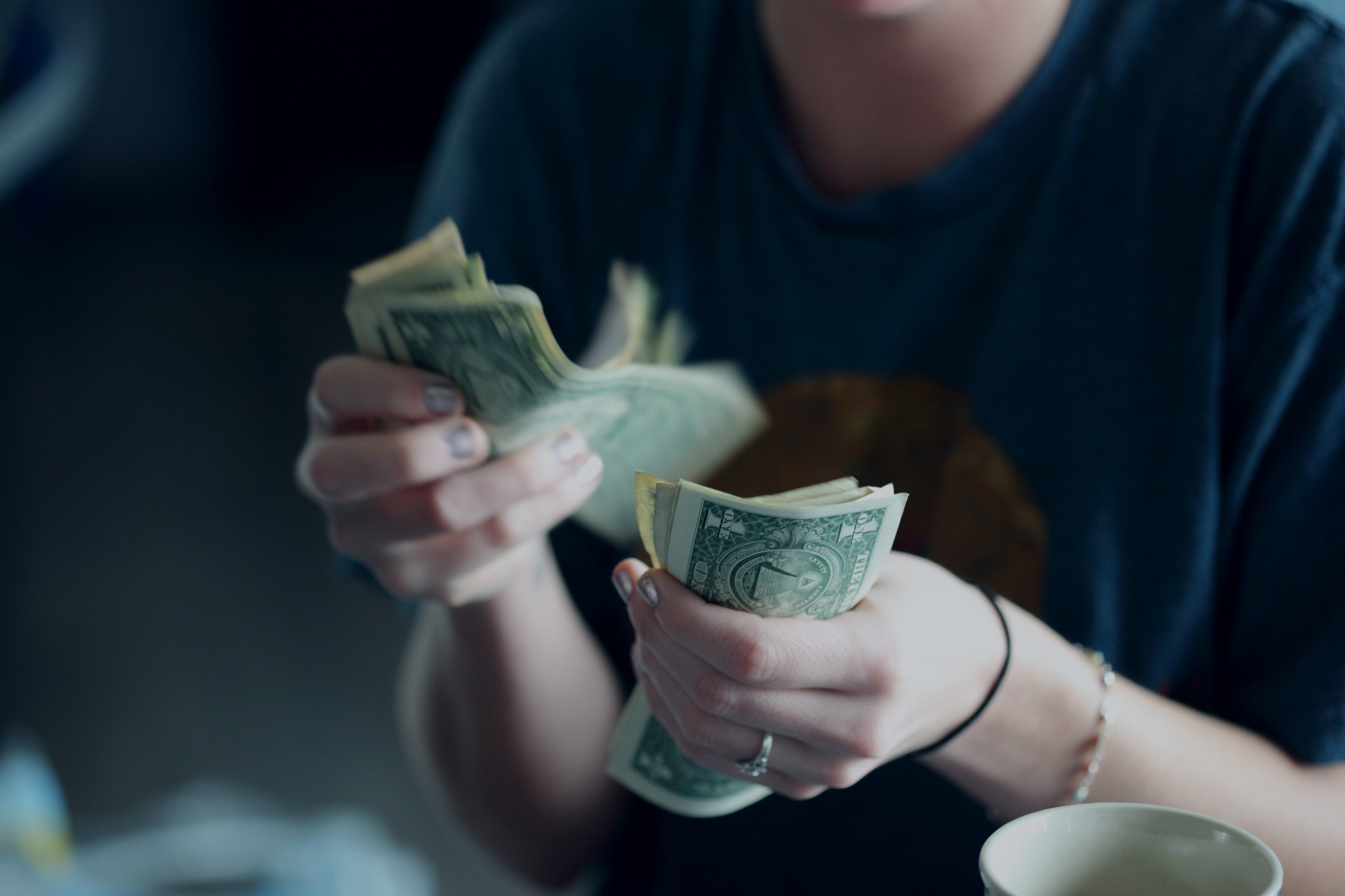 Person counts a wad of cash | Photo: Unsplash