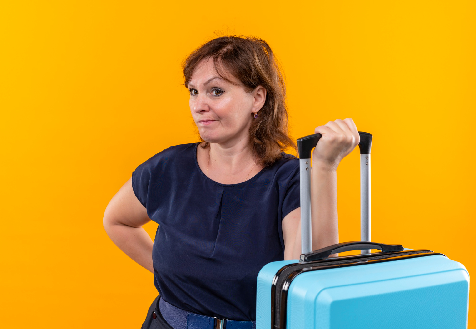 An annoyed-looking woman holding luggage | Source: Freepik