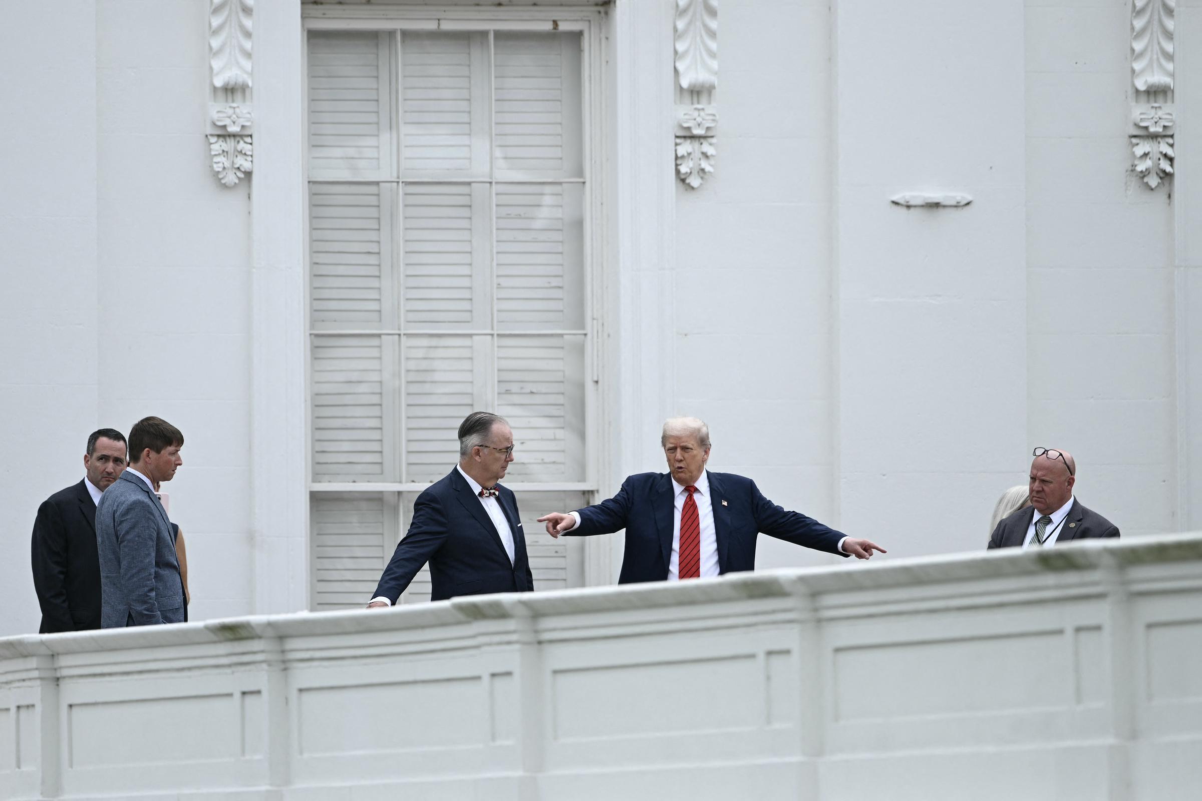 Donald Trump speaks with architect James C. McCrery while touring the West Wing roof of the White House in Washington, D.C., pointing out details as security and staff look on.