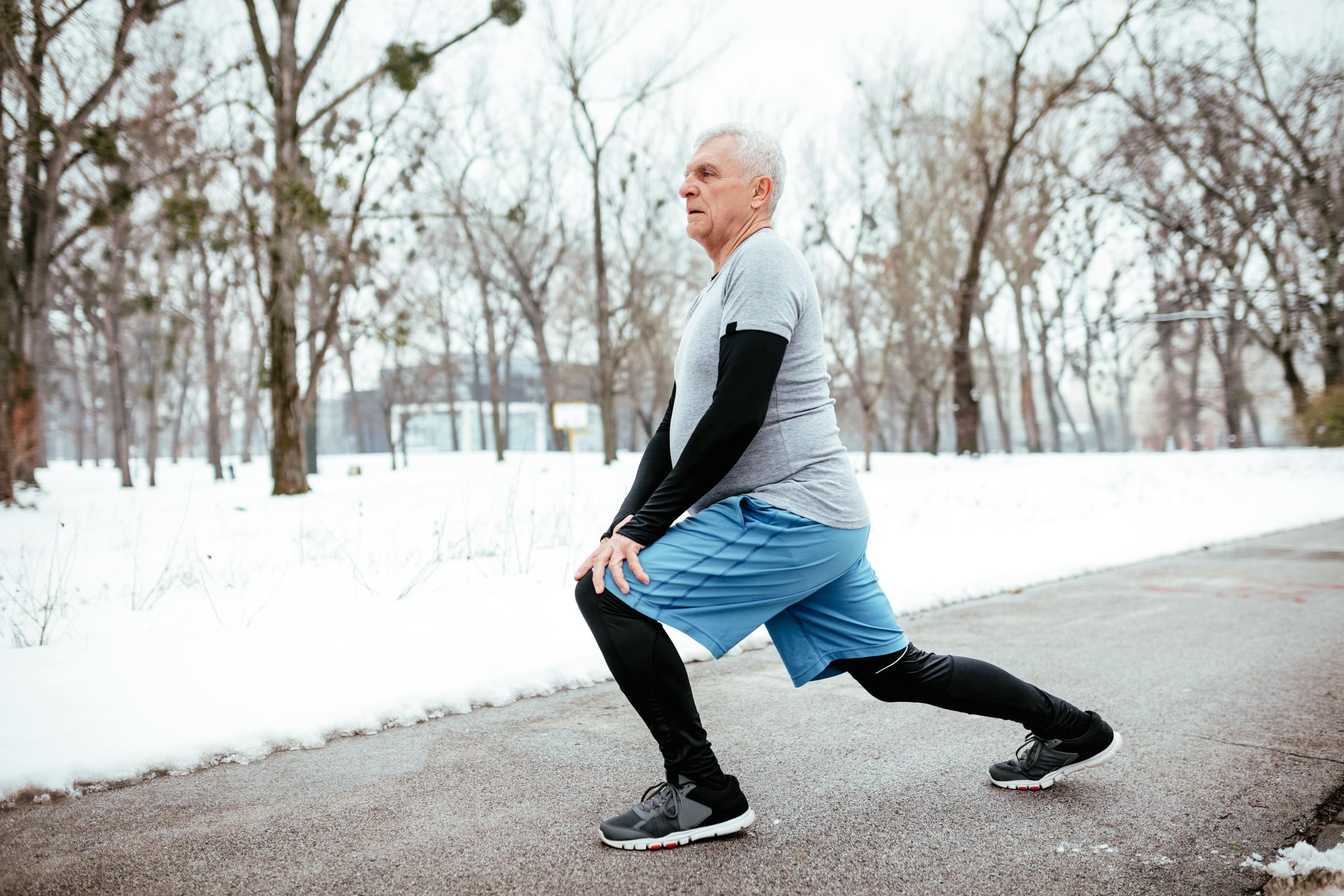 Older man doing stretching exercises on a snowy day | Source: Shutterstock