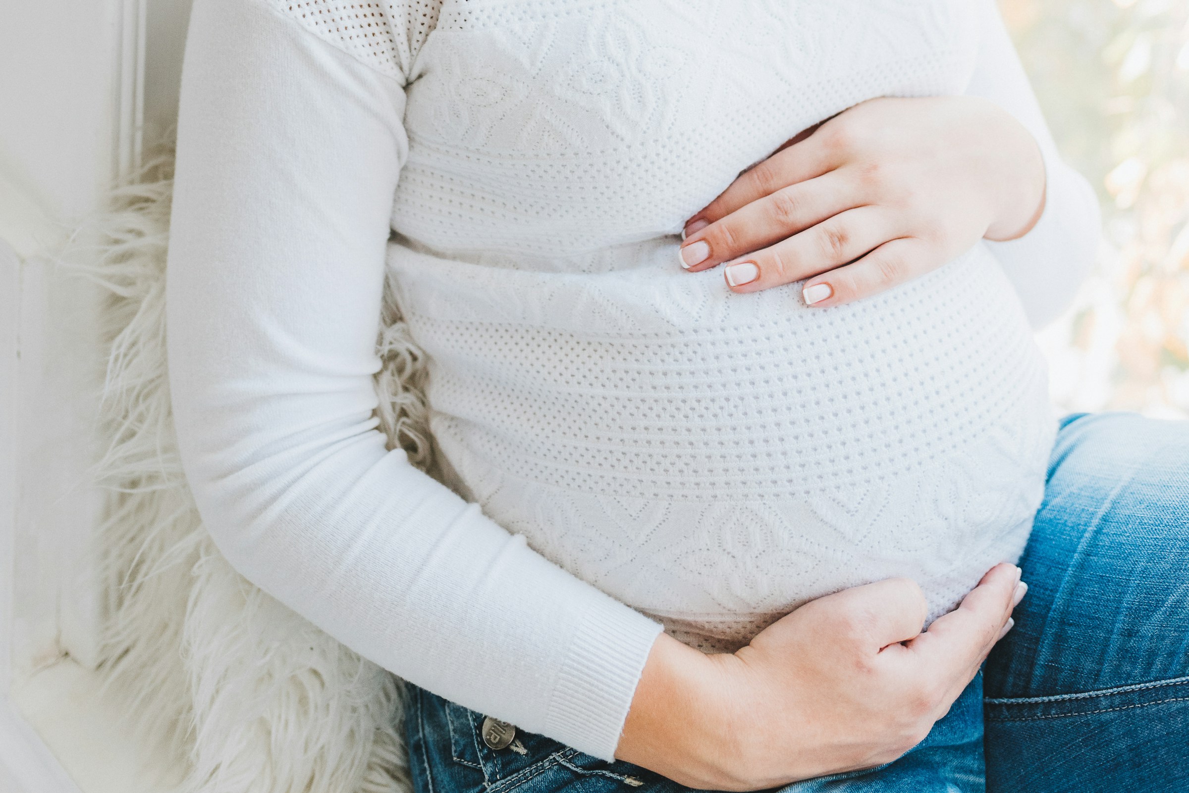 Close-up of a pregnant woman holding her baby bump | Source: Unsplash