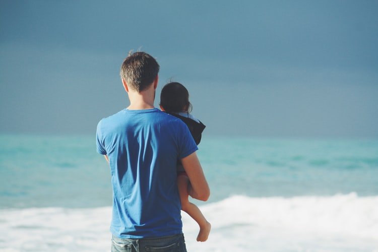 Un père qui porte son enfant dans ses bras. | Photo : Unsplash Un père qui porte son enfant dans ses bras. | Photo : Unsplash