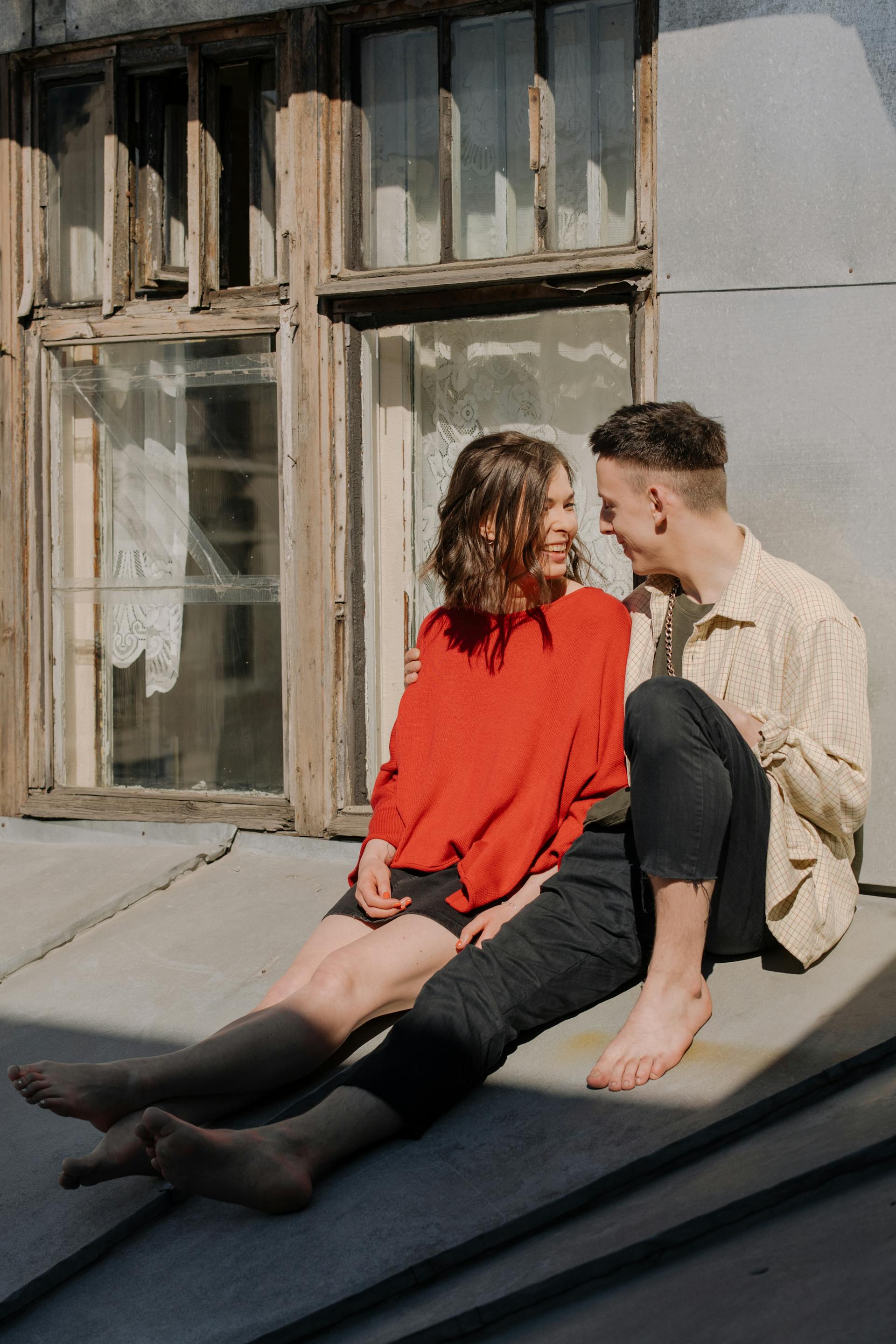 A couple laugh while sitting outside a building | Source: Pexels