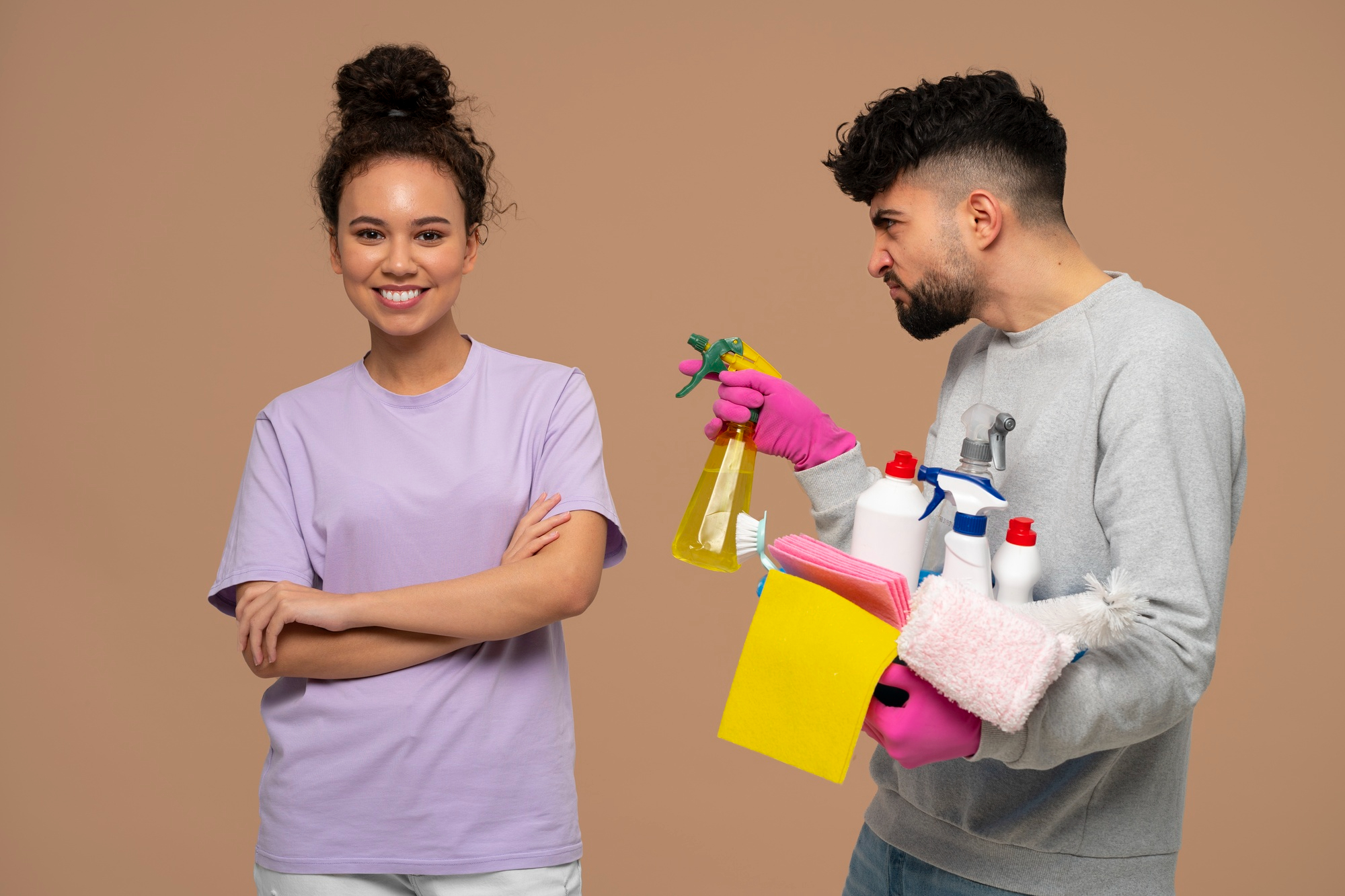 A woman smiling while a man playfully holds cleaning materials | Source: Freepik