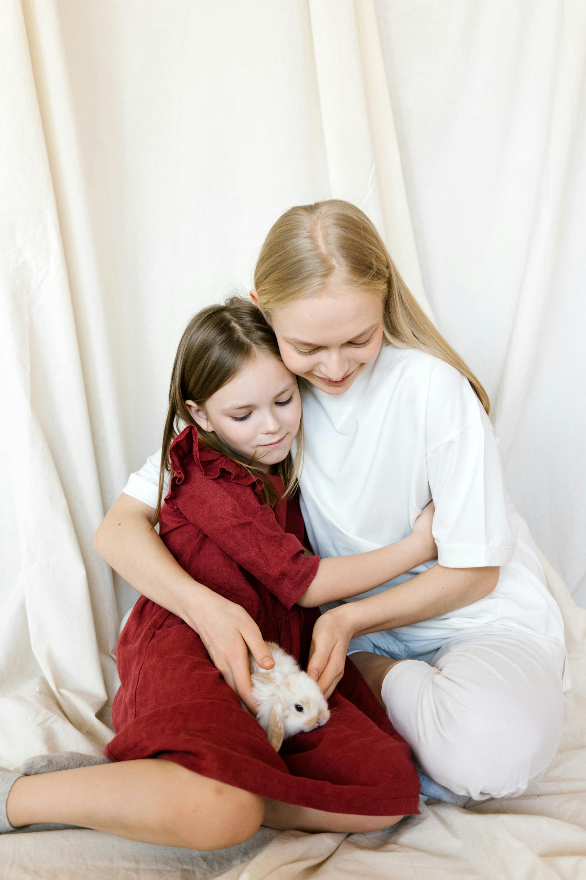 A young girl hugging her mom while looking at a rabbit | Source: Pexels