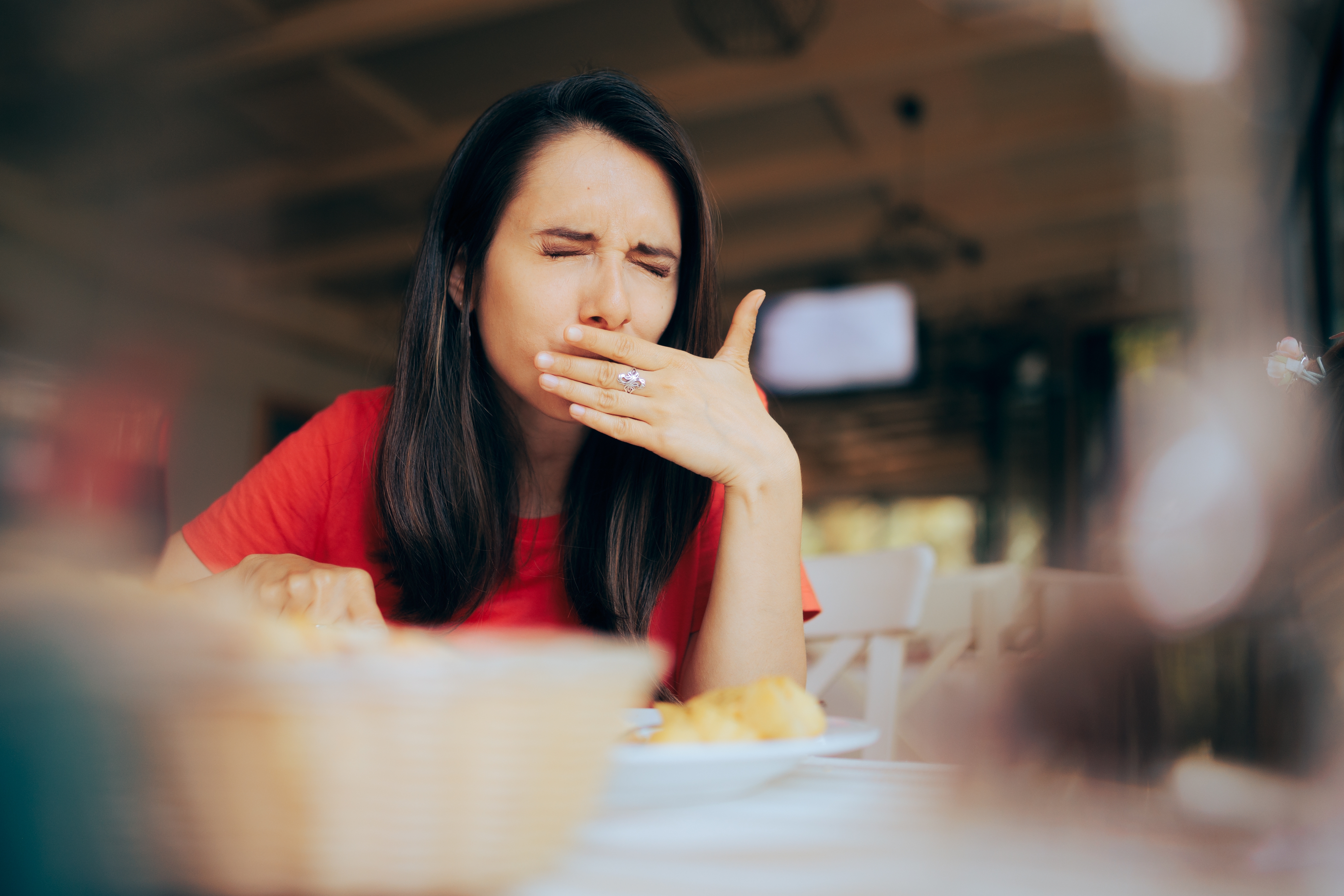 A woman feels discomfort while eating food | Source: Shutterstock