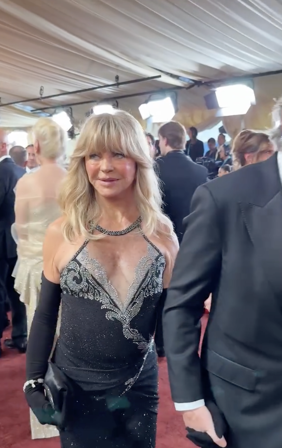 Kurt Russell leads the way along the carpet while Goldie Hawn follows nearby, surrounded by fans and media capturing the couple's arrival. | Source: Instagram/enews