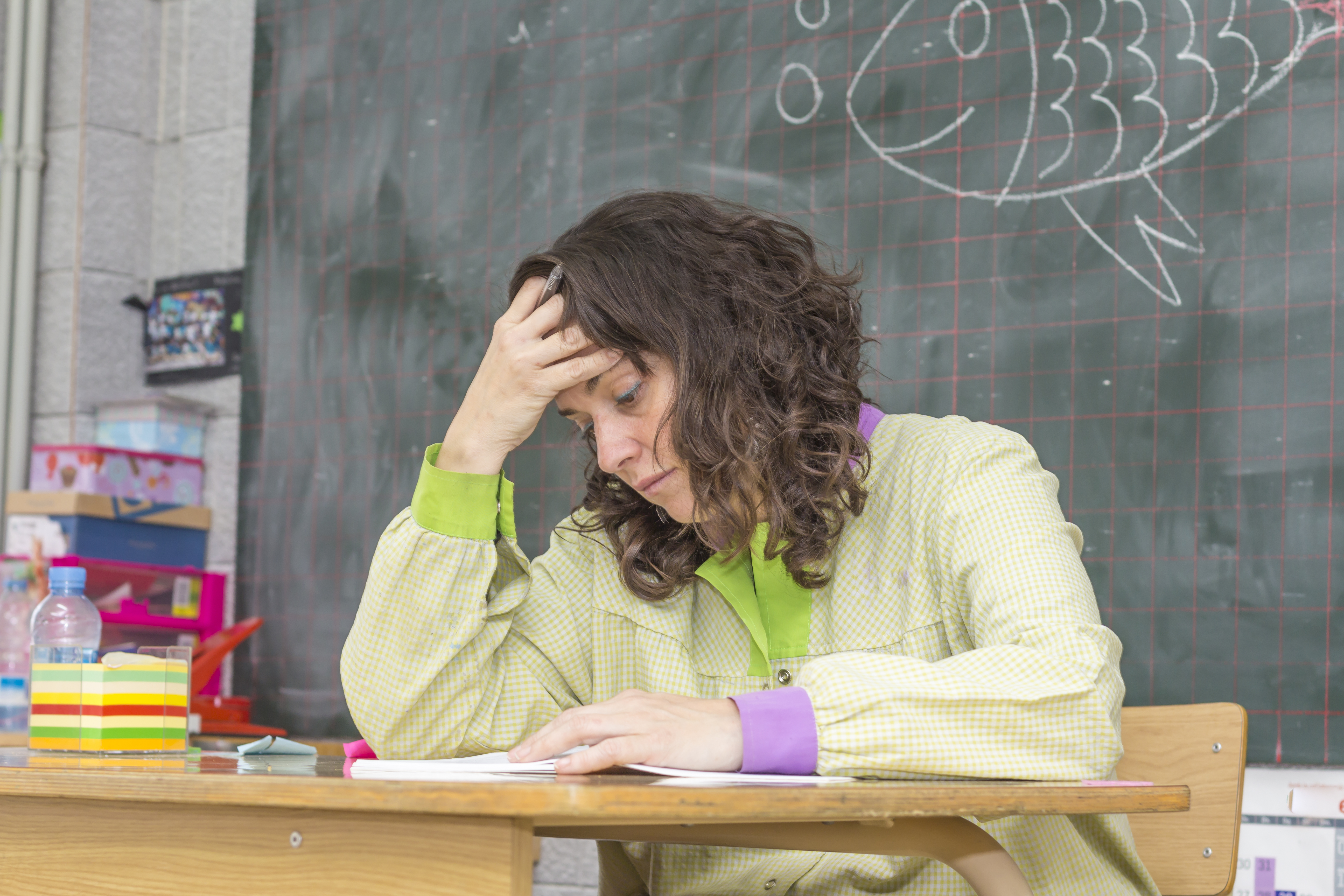 A frrustrated teacher at her desk | Source: Shutterstock