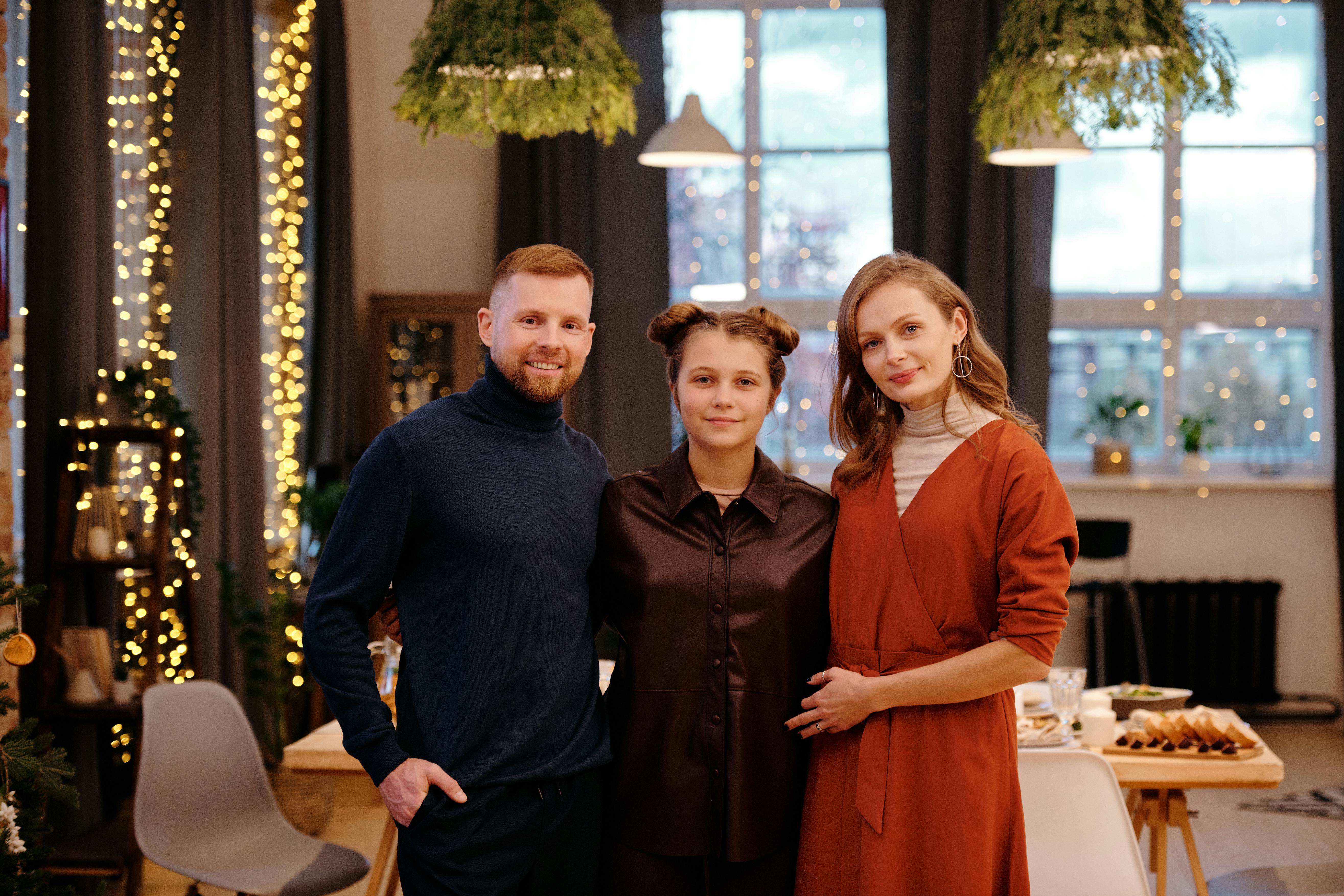 A happy family of three with a man, a young woman, and an older woman posing together | Source: Pexels