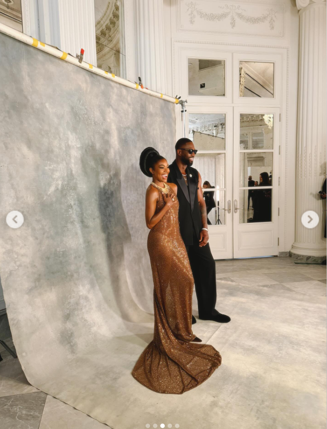Gabrielle Union smiles beside Dwyane Wade against a neutral backdrop, her bronze gown flowing to the floor. Dwyane's all-black look contrasts sharply, giving the portrait a clean, fashion-forward edge. | Source: Instagram/gabunion