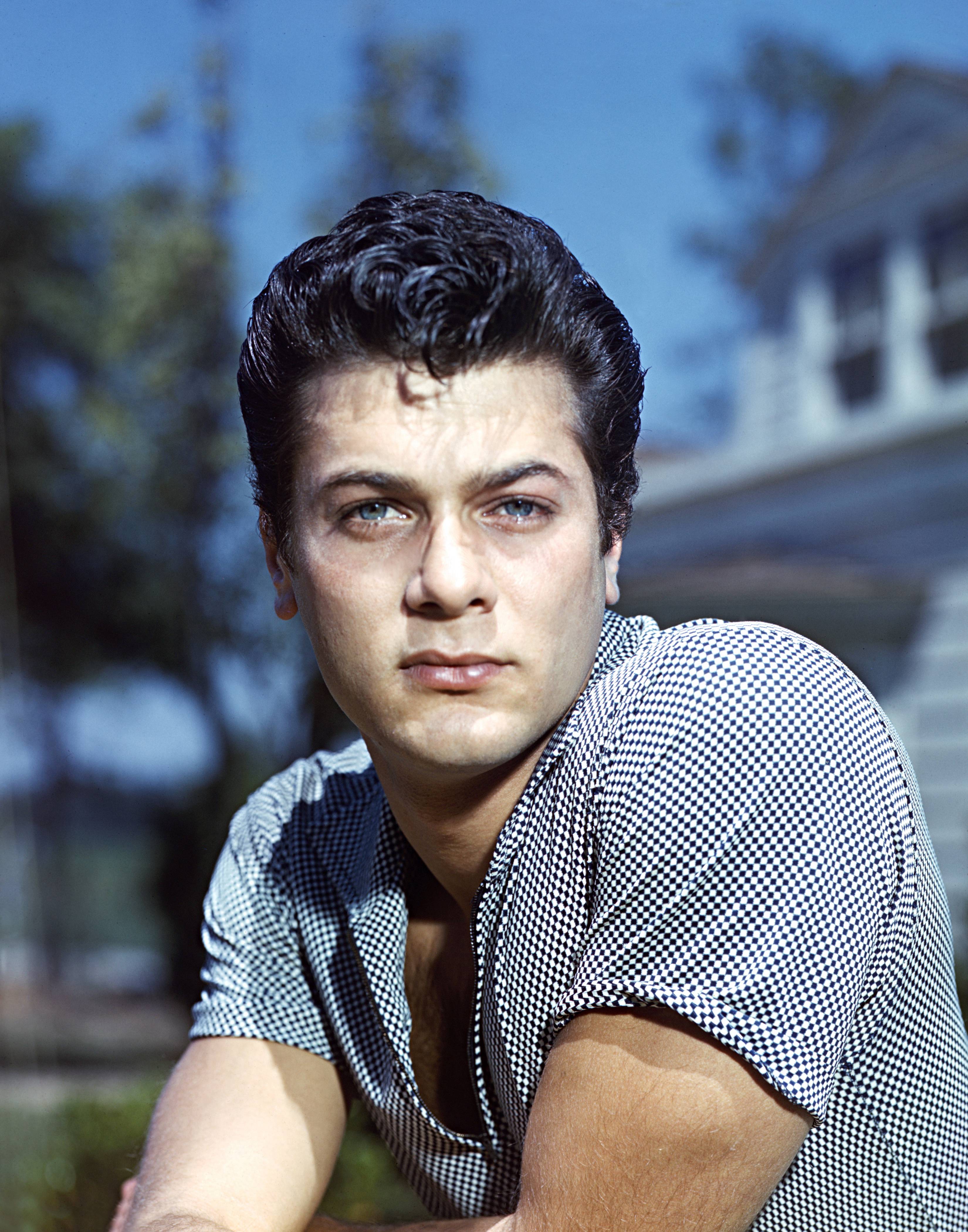 Tony Curtis posing for an image while wearing a short-sleeved black-and-white check shirt circa 1955 | Source: Getty Images