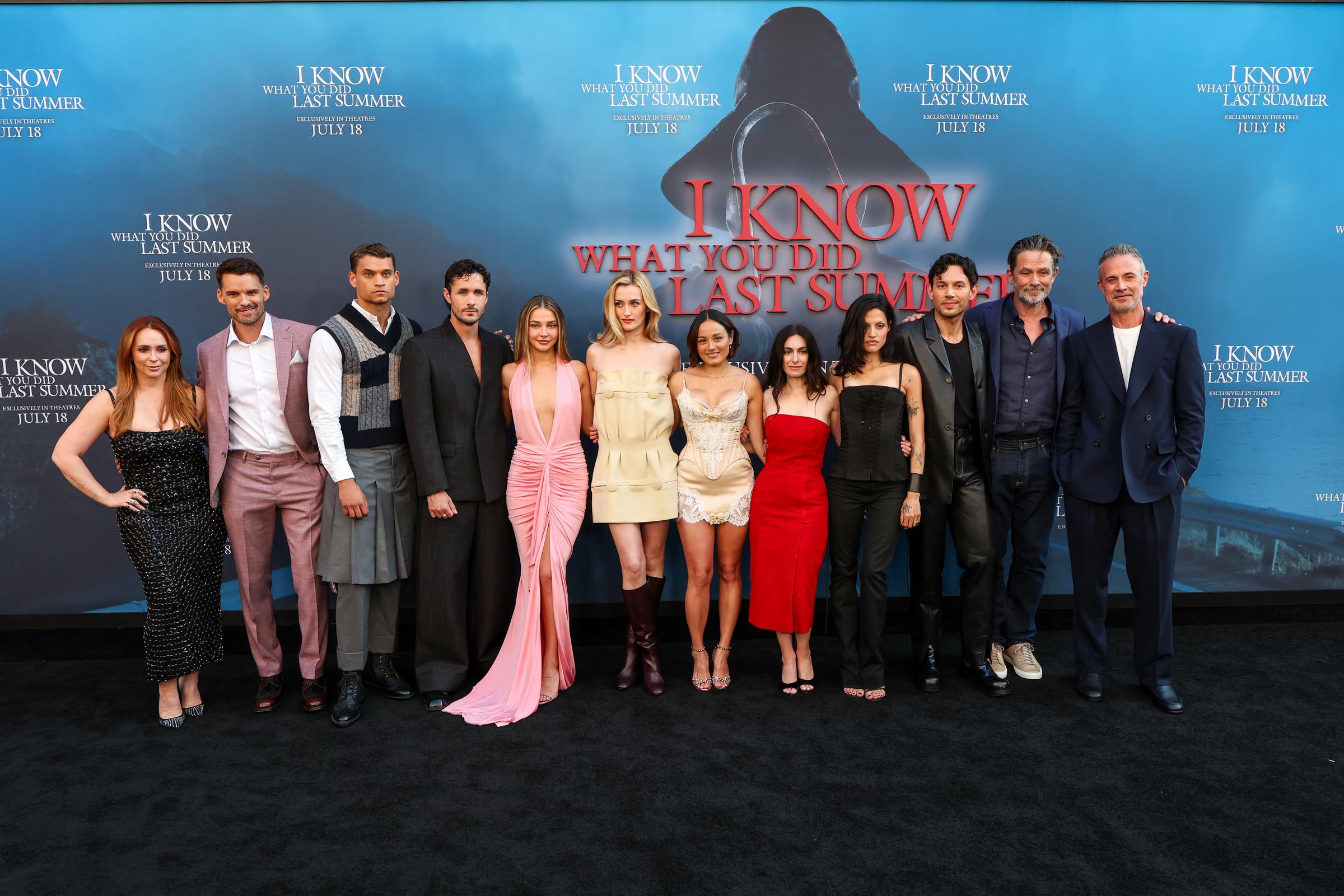 Jennifer Love Hewitt joins her co-stars on the carpet for a full cast photo at the premiere of "I Know What You Did Last Summer," standing confidently at the far left in a sparkling black dress.