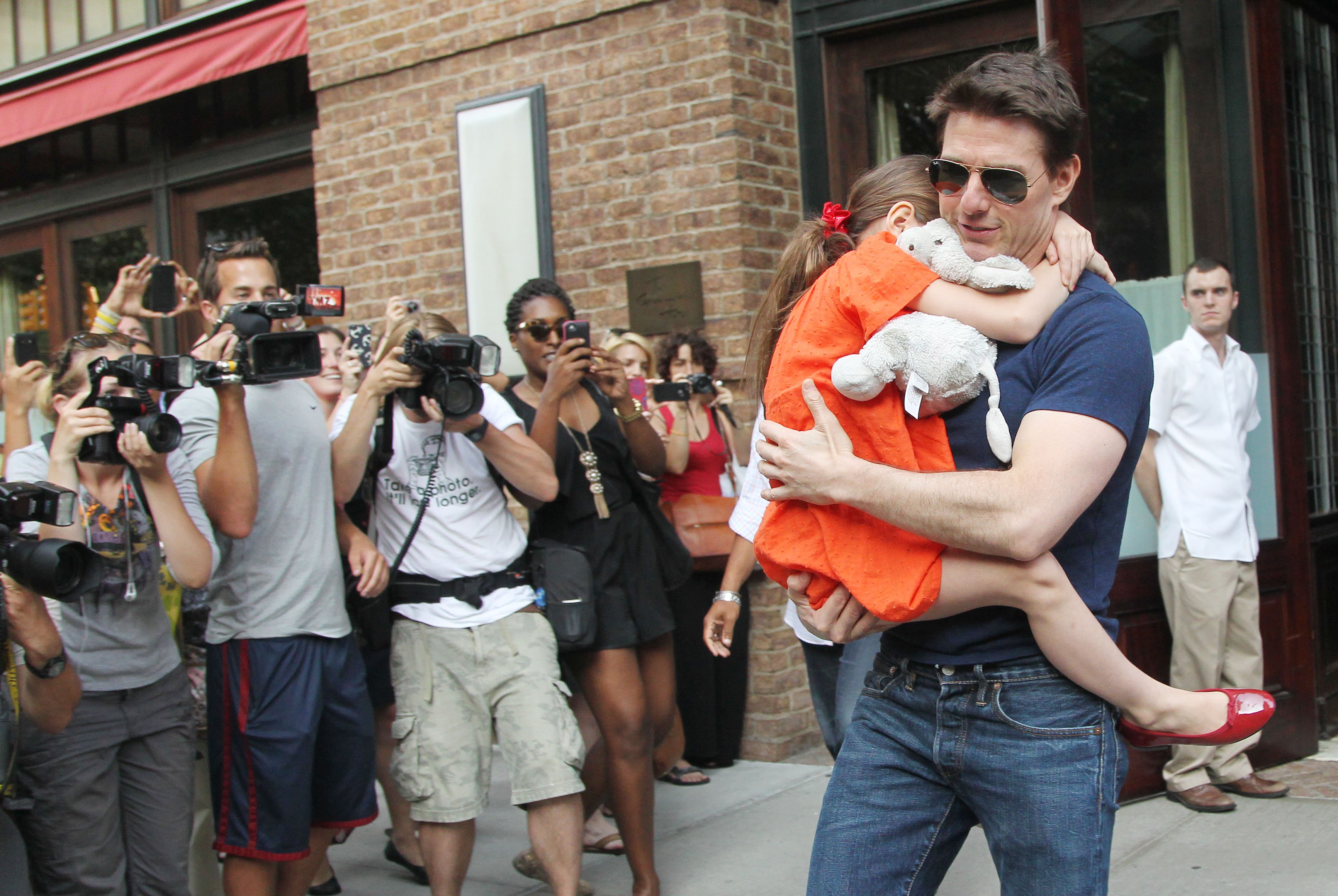 Tom Cruise carries Suri as they exit a building in New York City in 2012. | Source: Getty Images