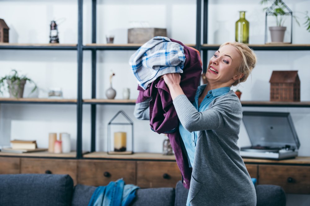 Angry woman throwing clothes in the living room | Photo: Shutterstock/LightField Studios