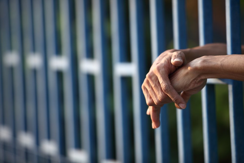 Manos de preso a través de barrotes. || Fuente: Shutterstock