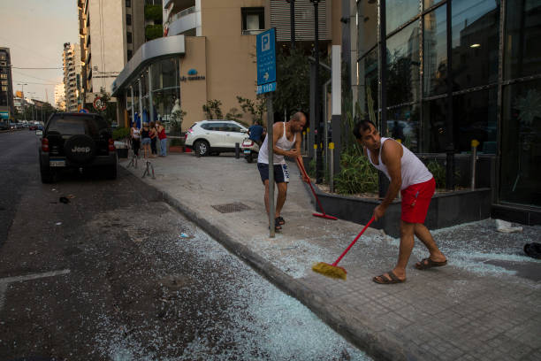 Deux hommes balayant la rue après les deux explosions survenues à Beyrouth | Photo : Getty Images