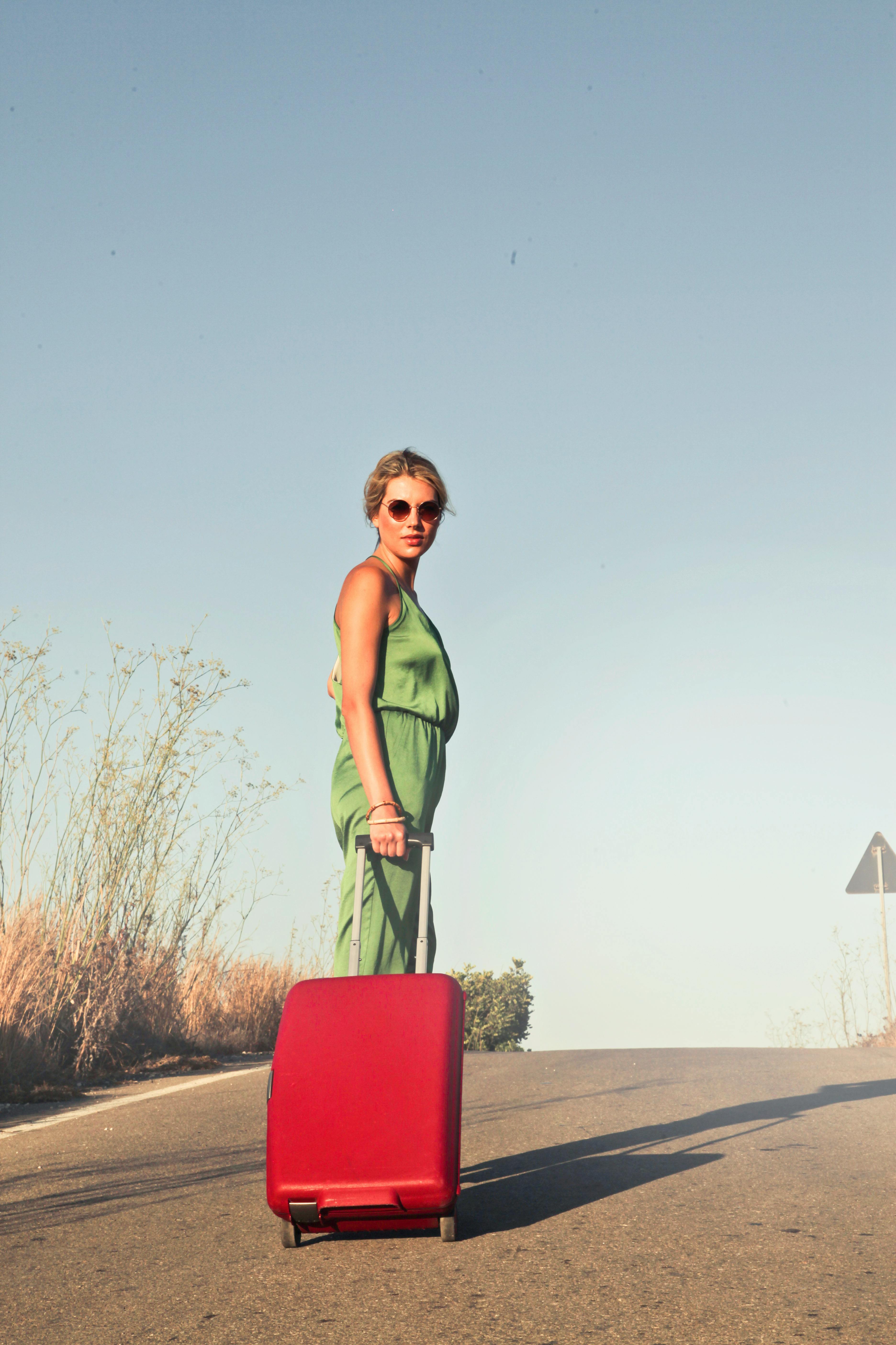 A woman walking with a red suitcase | Source: Pexels