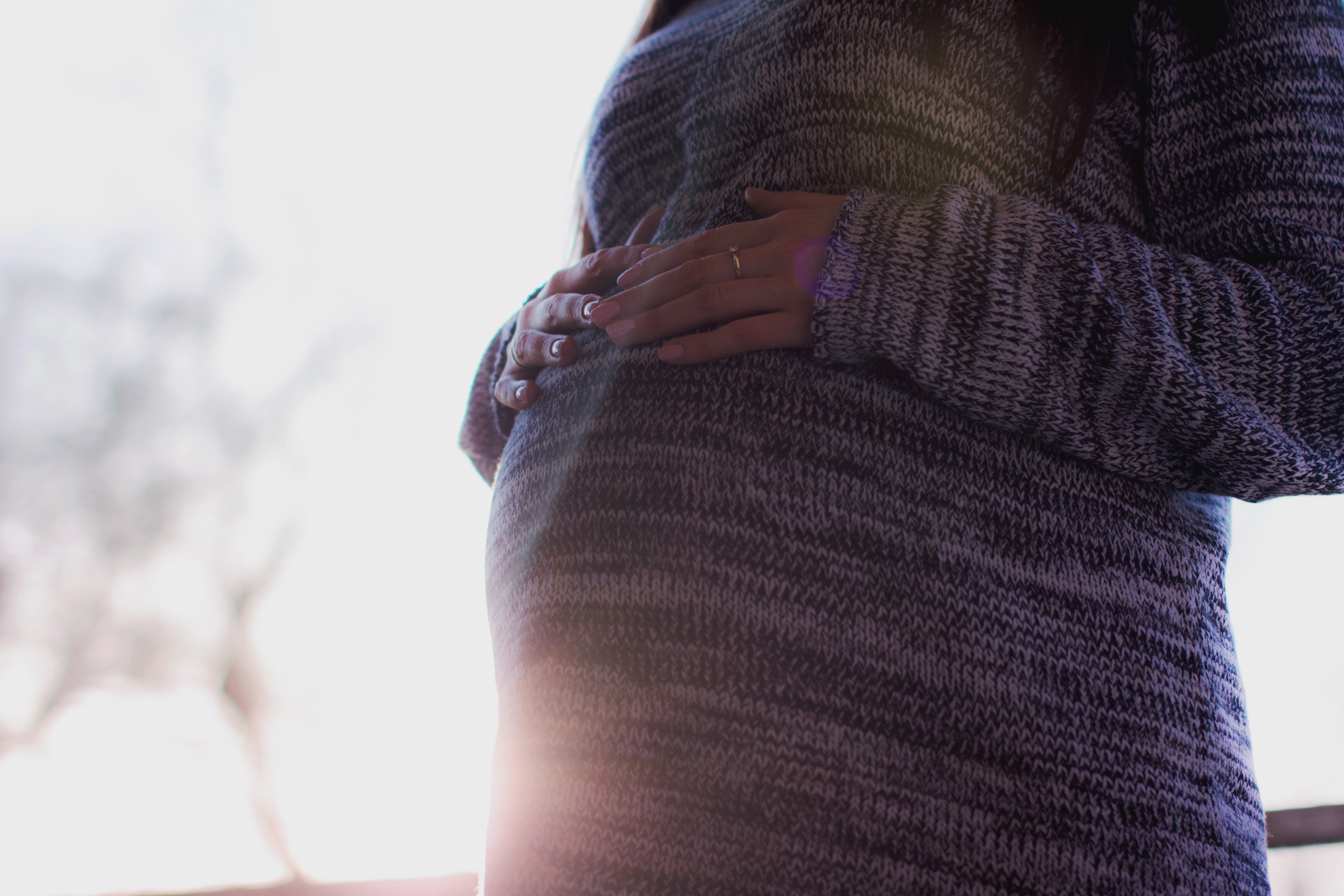 Pregnant woman placing her hands on her baby bump. | Source: Unsplash