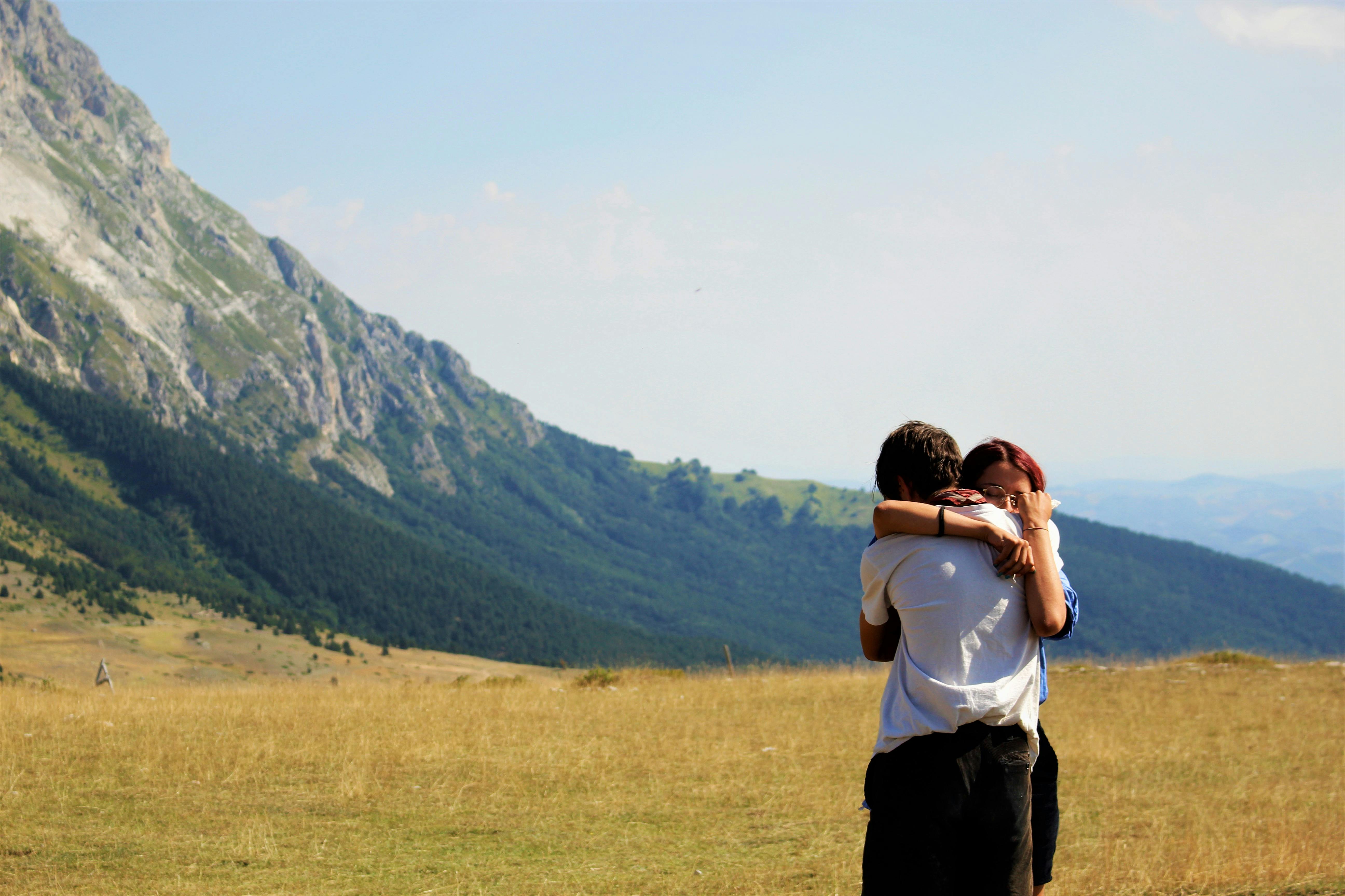 A couple hugging on a grass field | Source: Pexels
