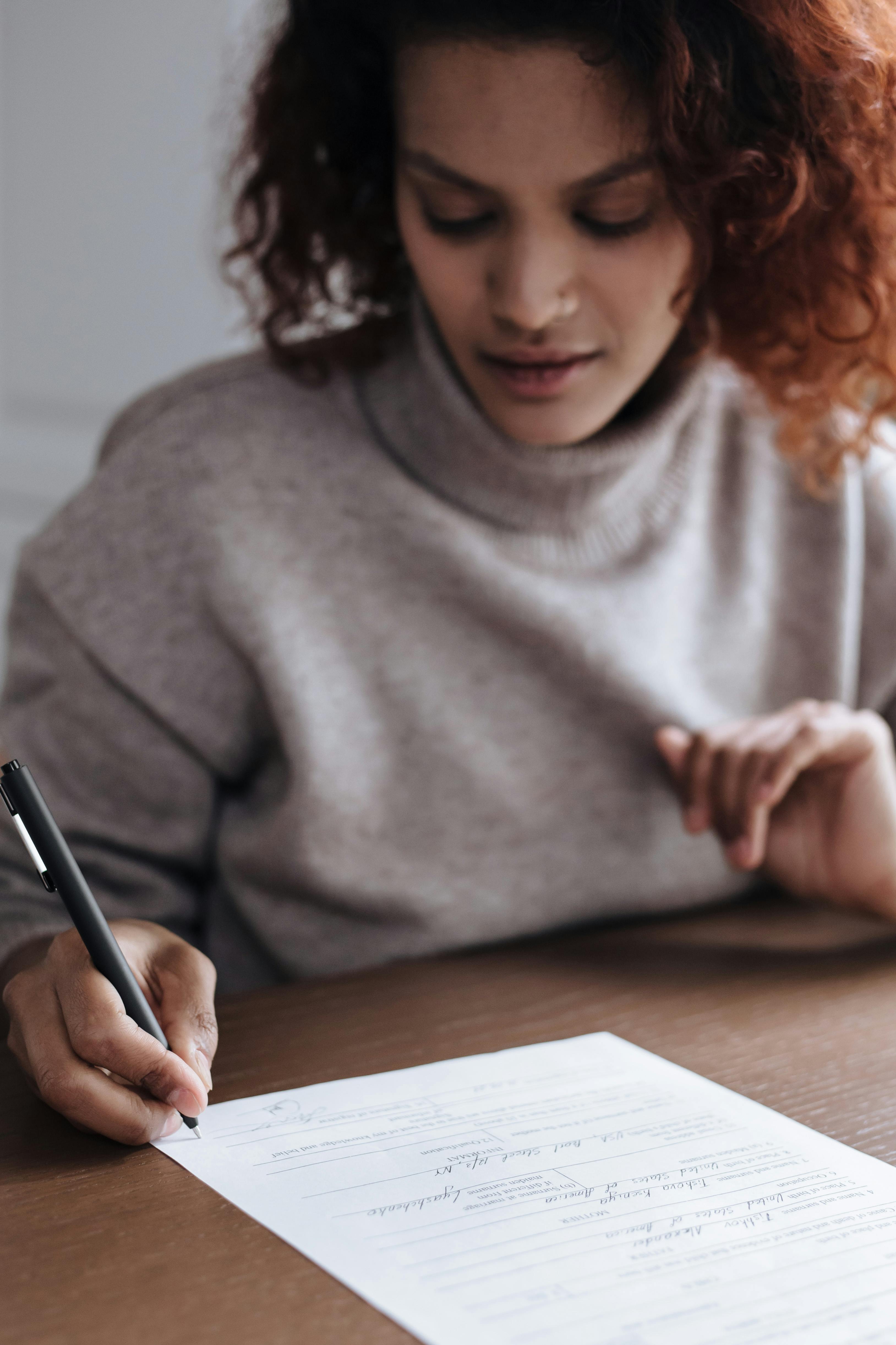 A woman signing documents | Source: Pexels