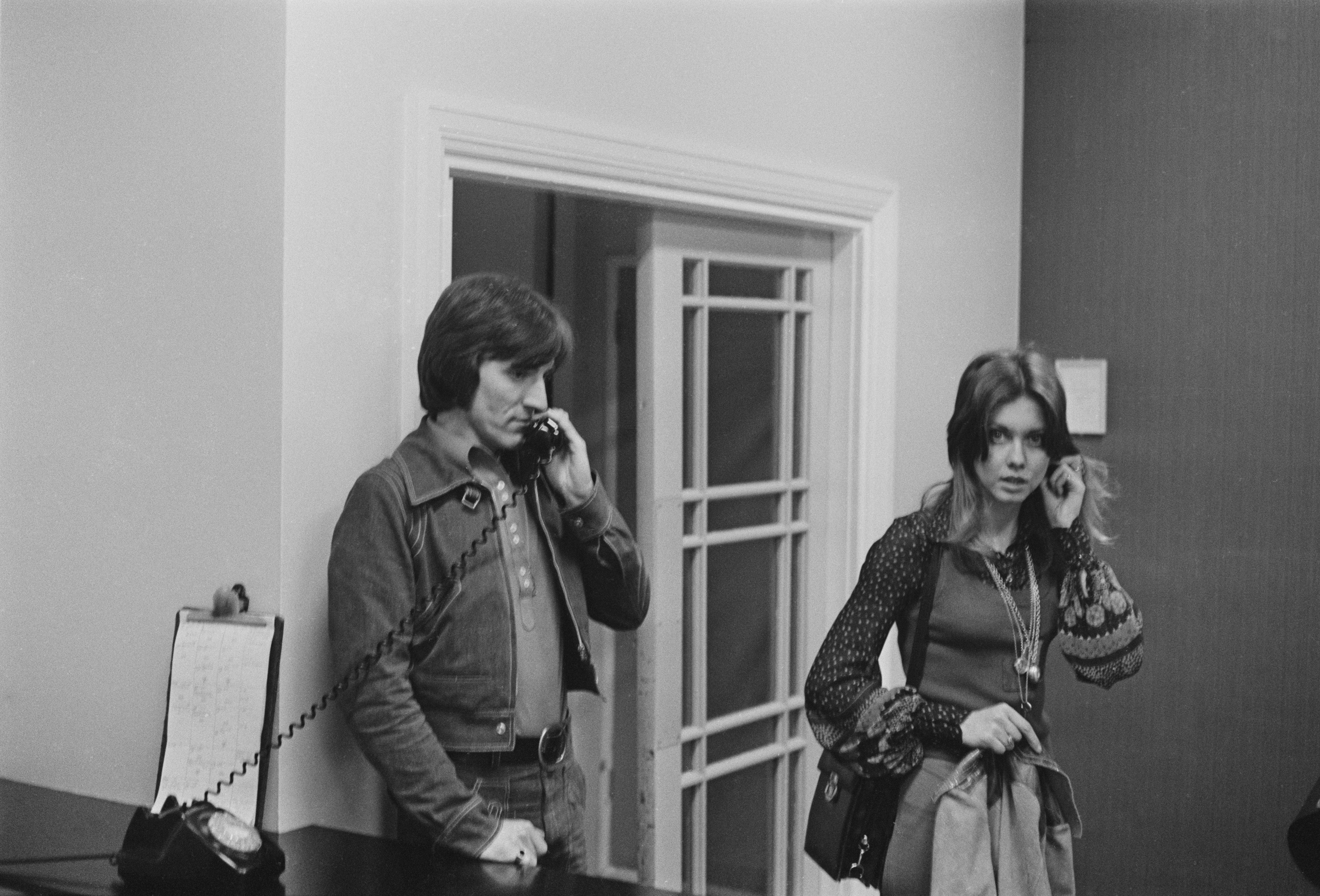 Bruce Welch speaking on the telephone as Olivia Newton-John stands to the side in a recording studio in 1972 | Source: Getty Images