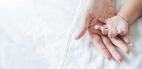 Une maman tenant la main de son bébé | Photo : Shutterstock