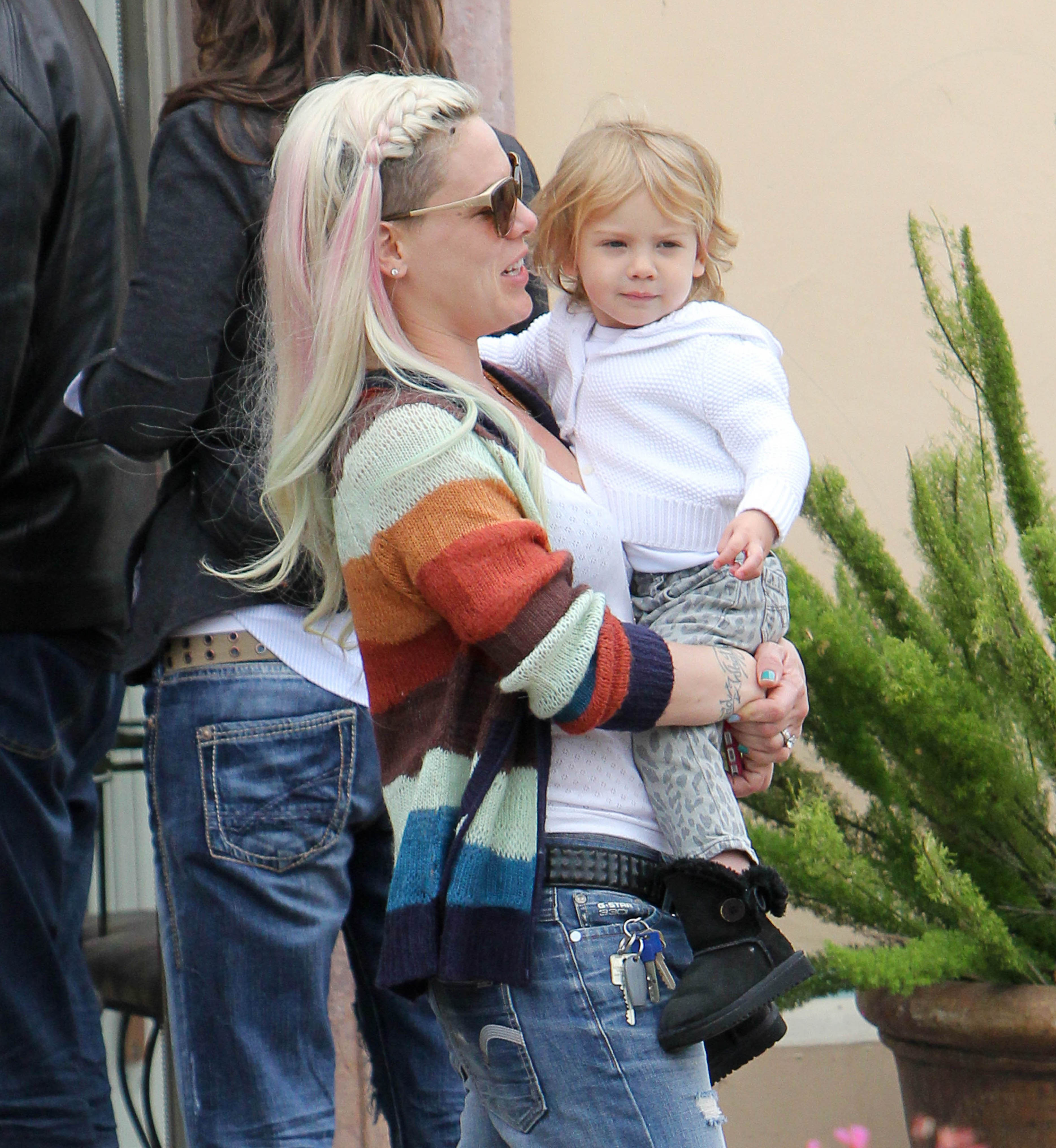Pink, also known as Alecia Moore, carries Willow Sage Hart in Los Angeles on June 8. Pink wears sunglasses and a striped cardigan, while Willow appears calm in a white sweater and patterned pants.