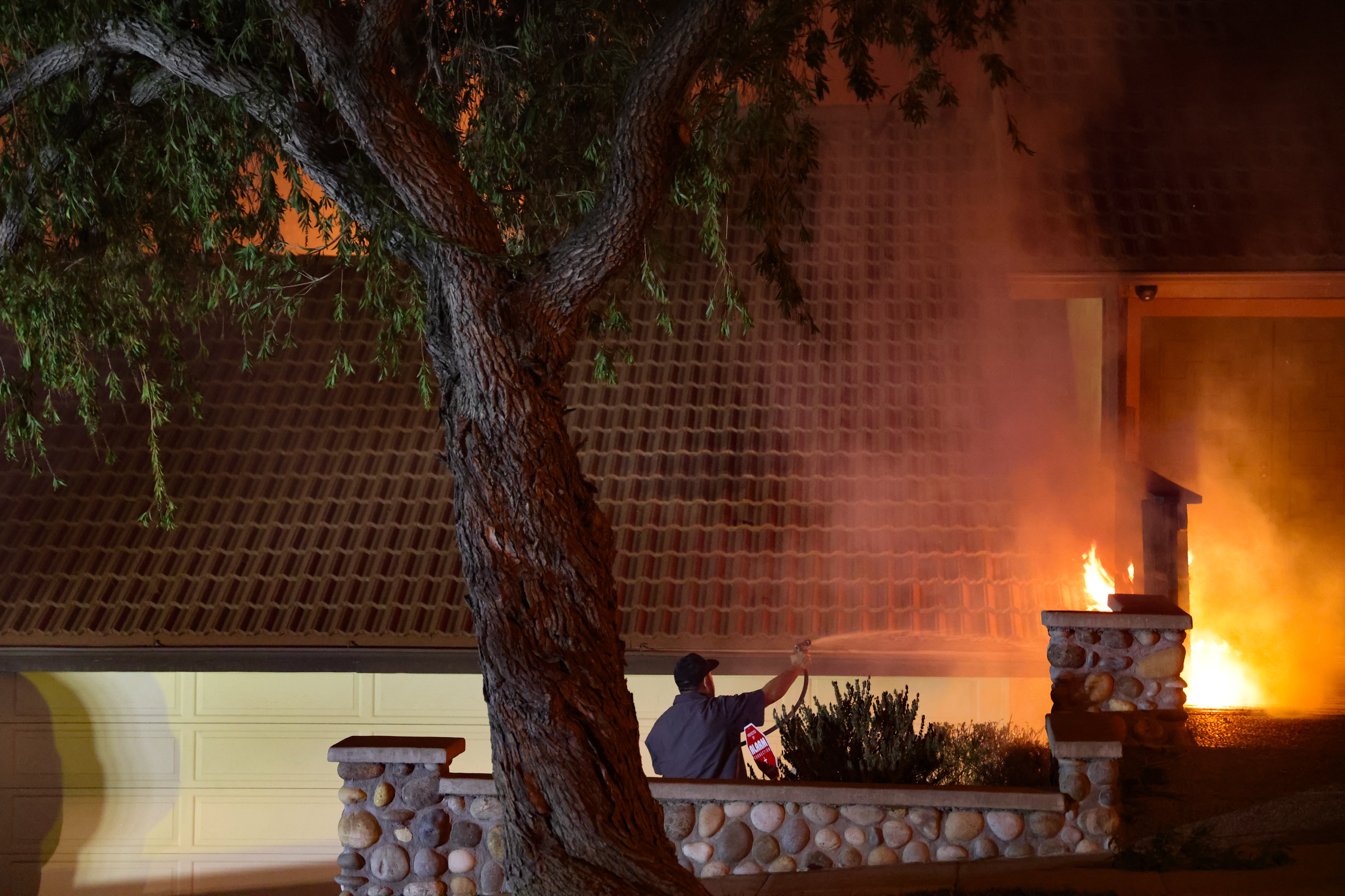 A civilian attempting to douse a house on fire in Altadena, California on January 7, 2025. | Source: Getty Images