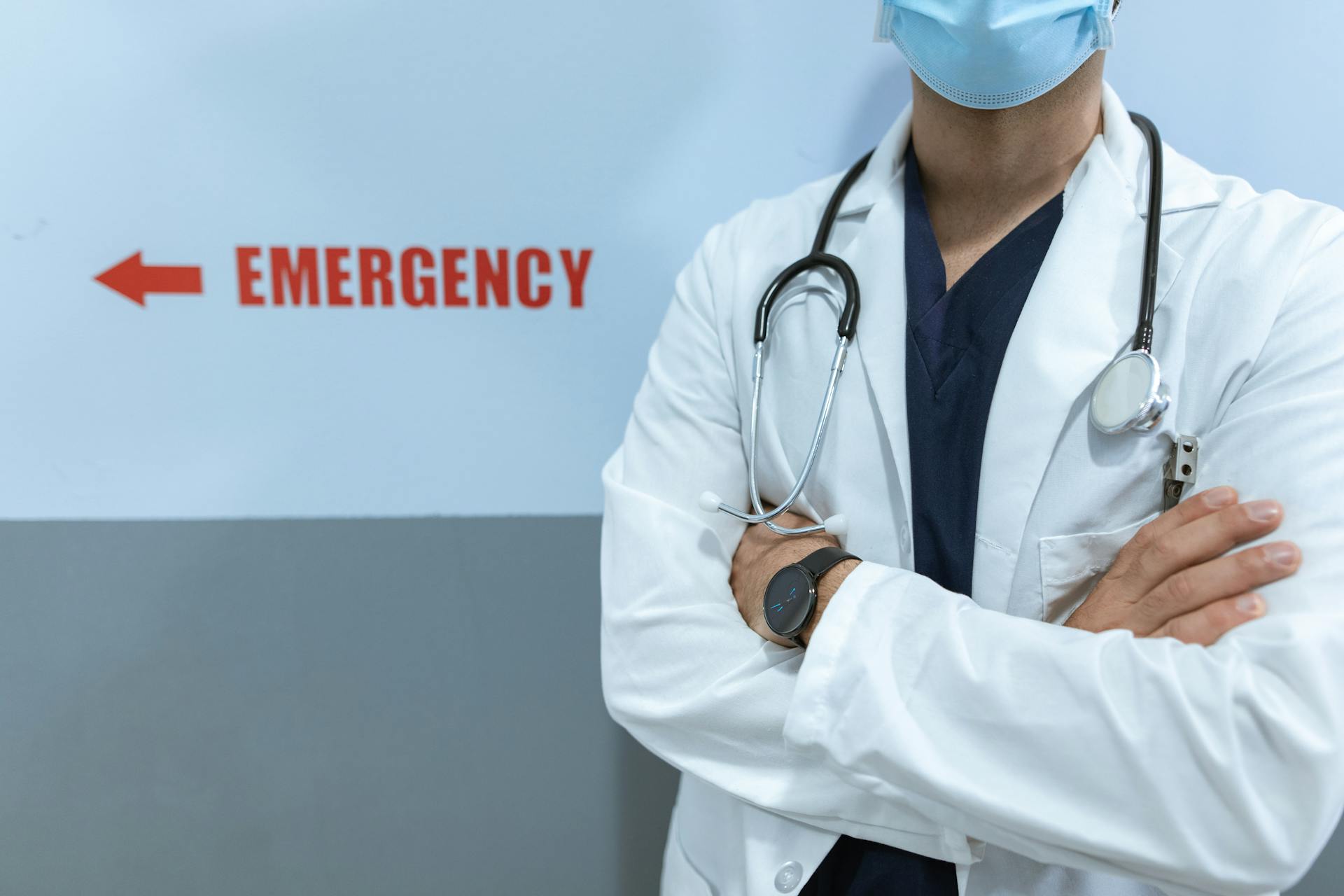 A doctor standing next to the emergency sign on the wall | Source: Pexels