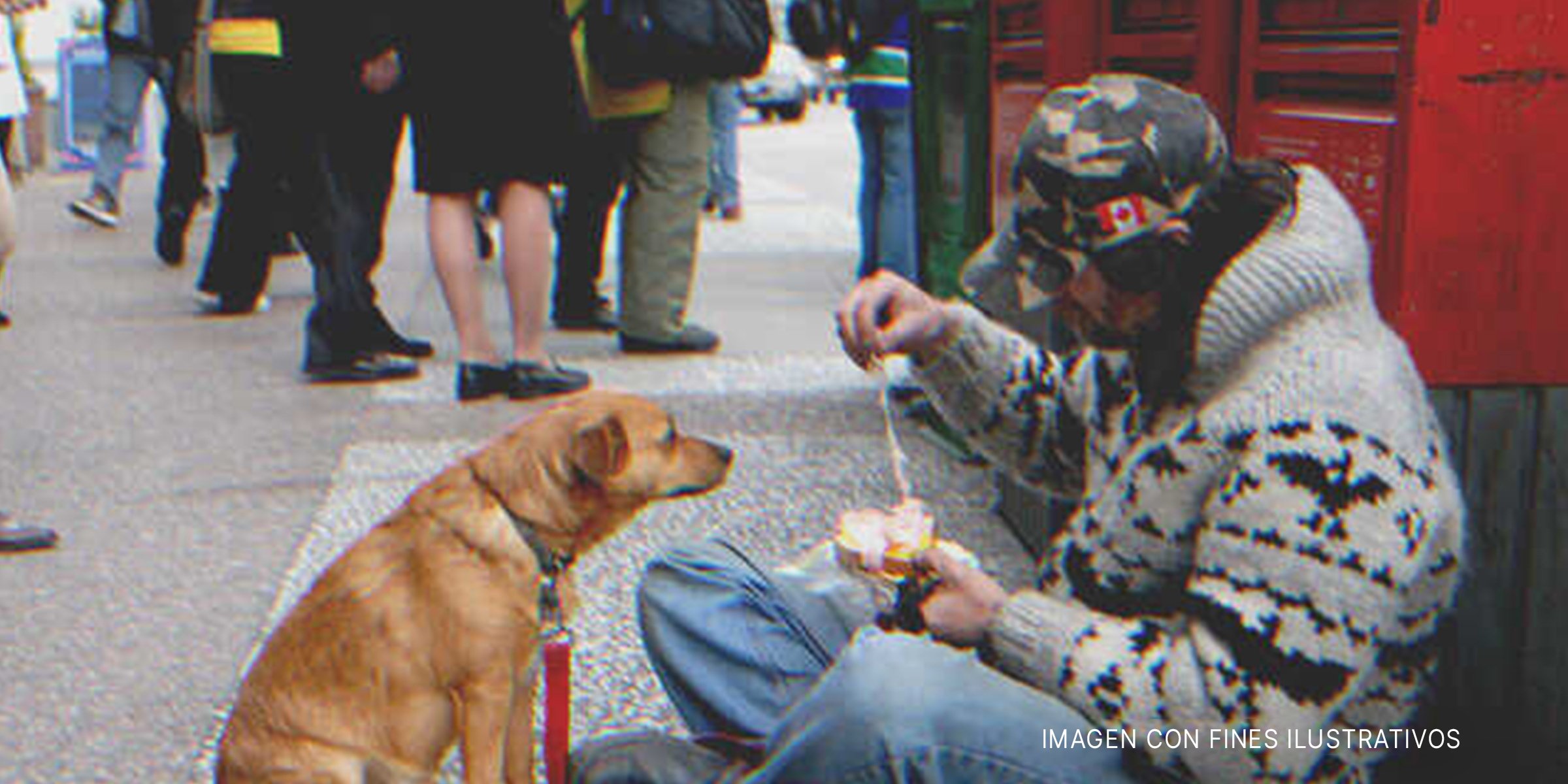 Hombre sin hogar alimentando a un perro en la calle | Fuente: Shutterstock