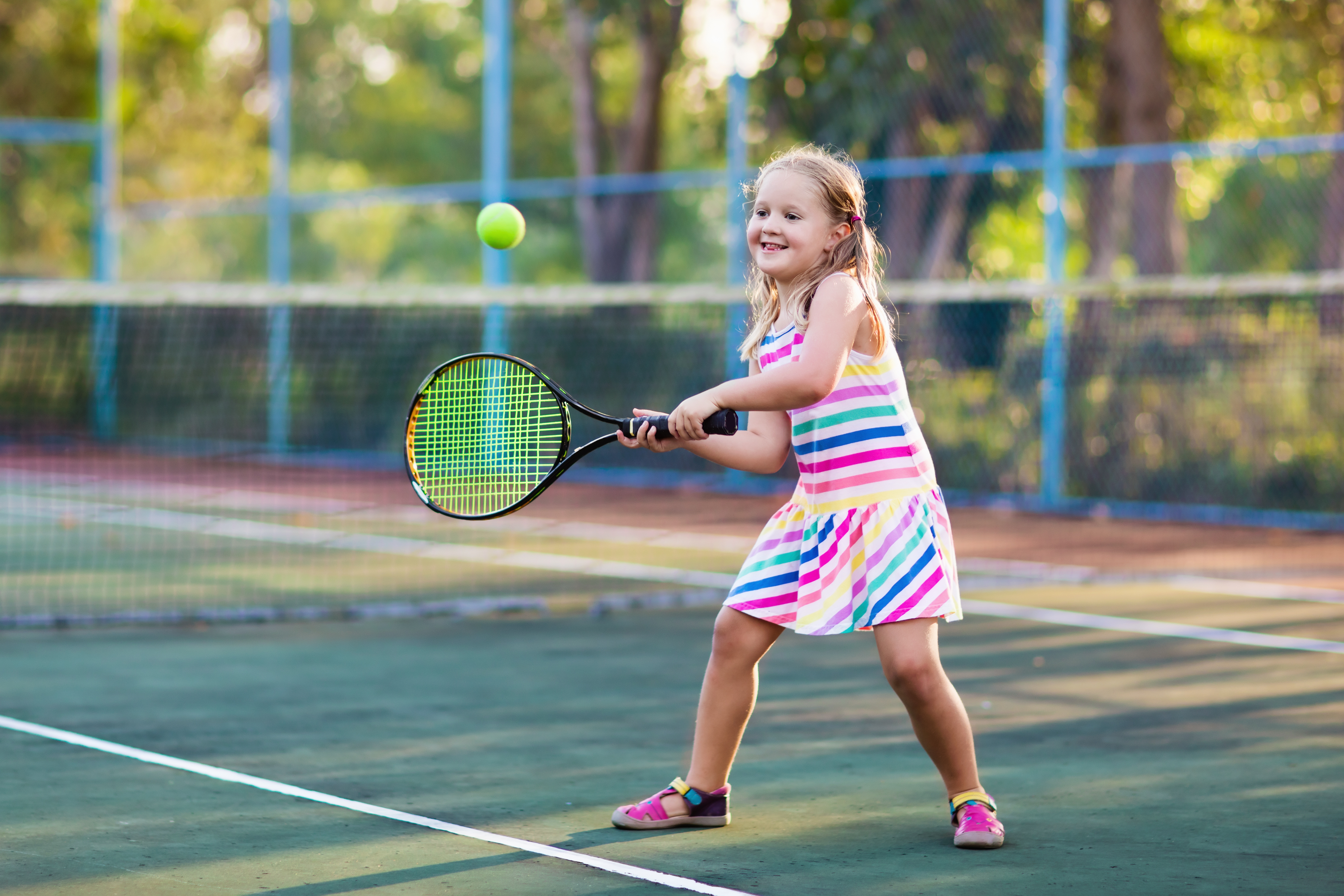 A little girl playing tennis on a court | Source: Shutterstock