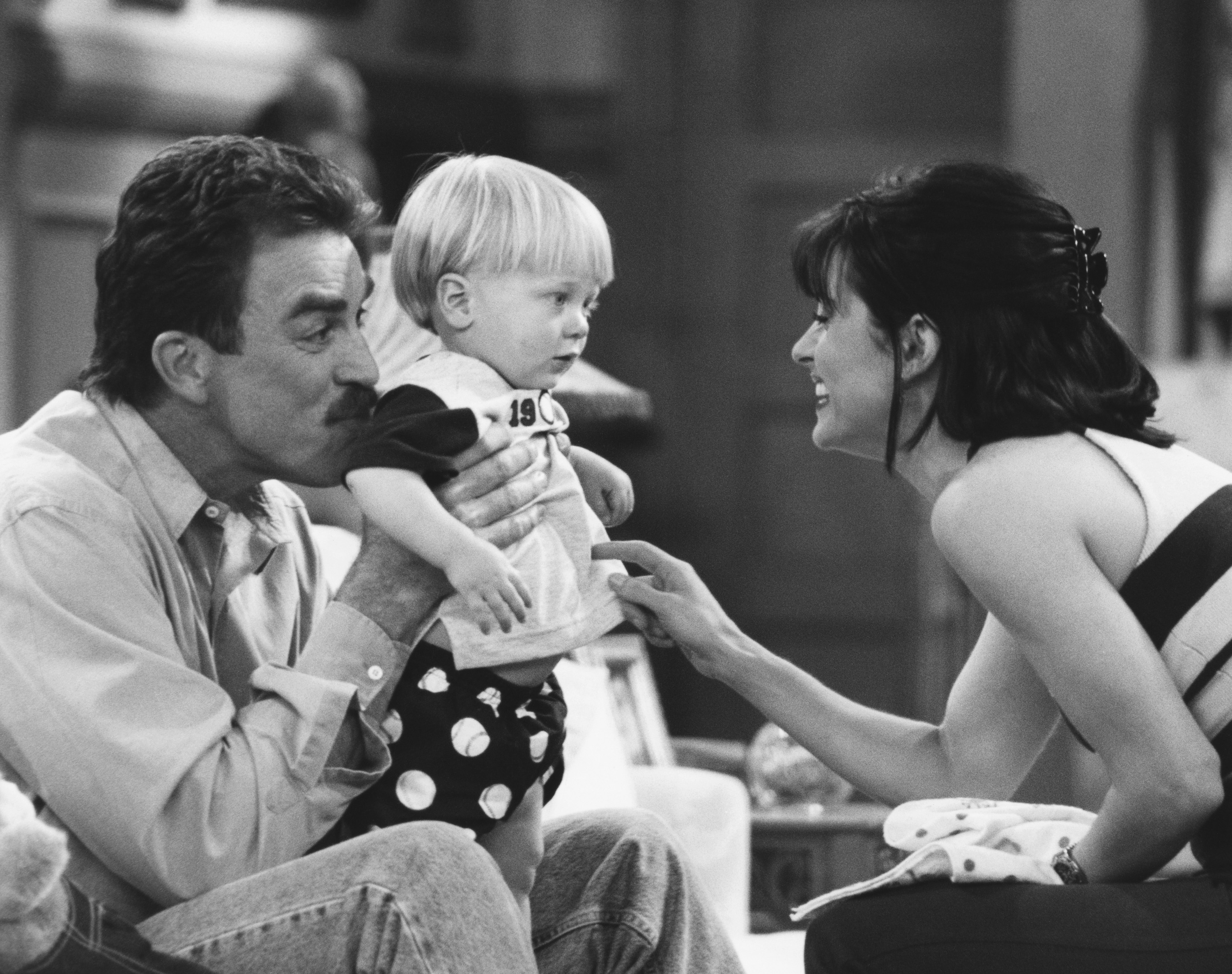 Tom Selleck (holding a baby) and Courteney Cox on the set of "Friends" on May 16, 1996 | Source: Getty Images