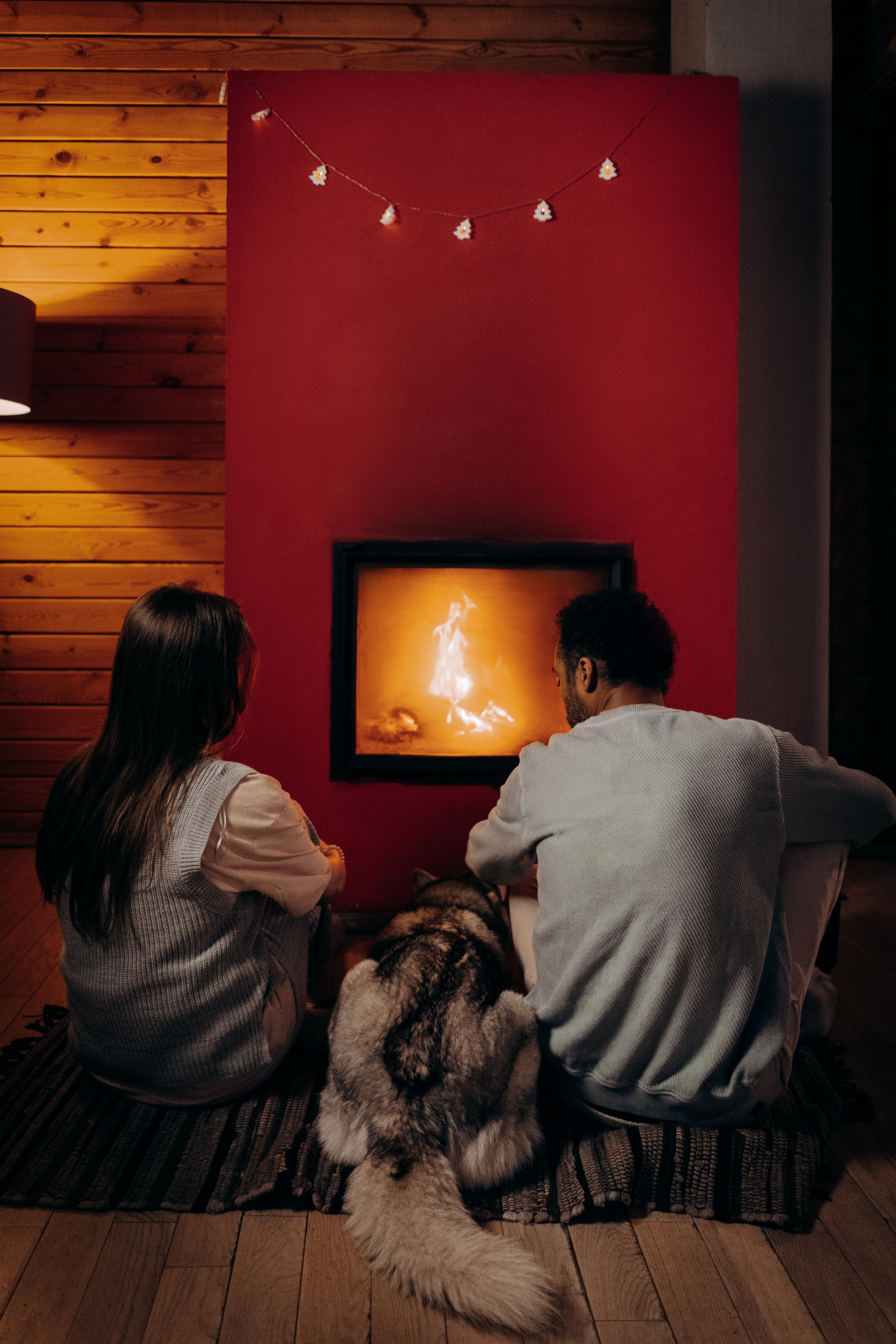 A couple sitting in front of a fireplace with their dog. | Source: Unsplash