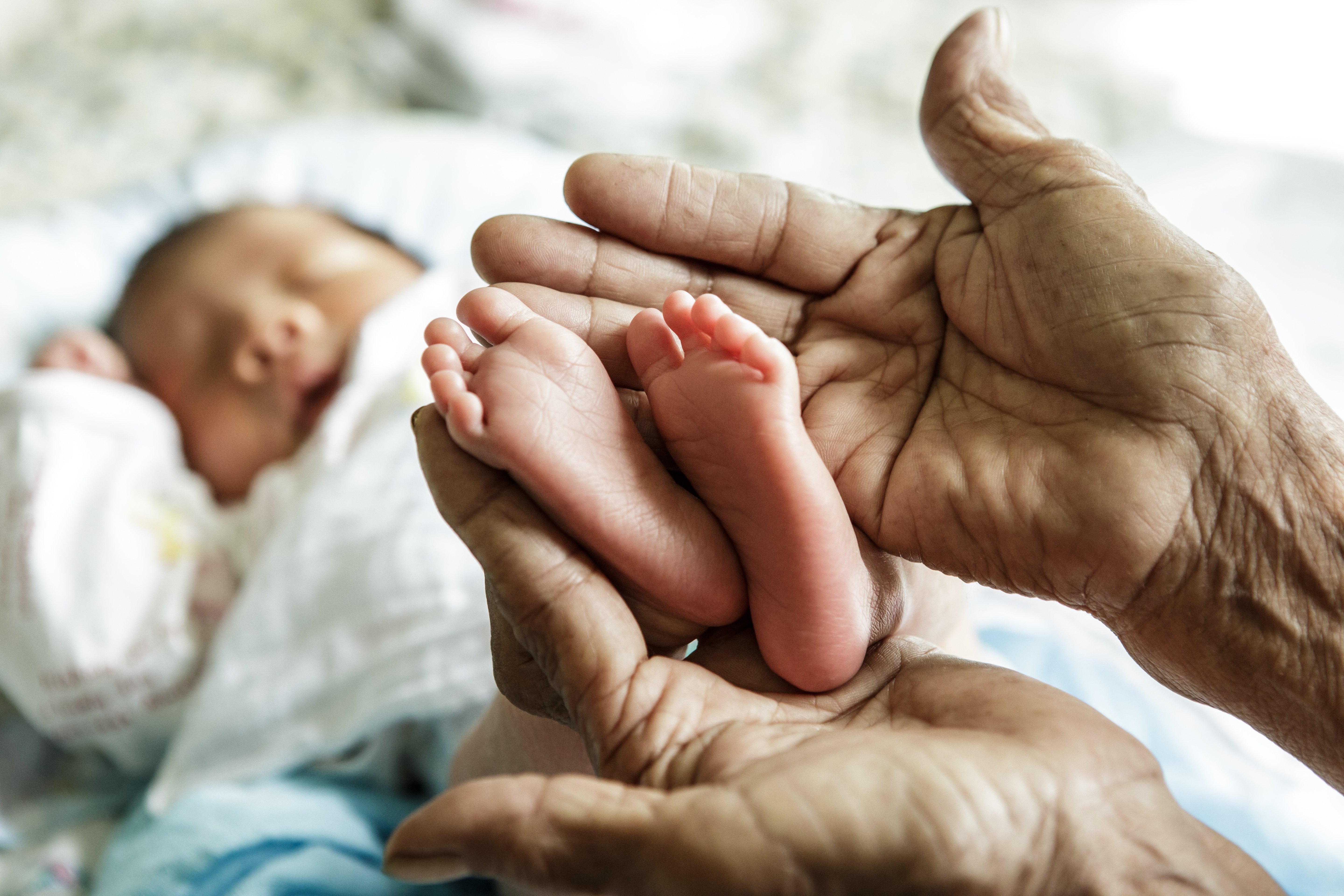 Ältere Frau hält die Füße eines Säuglings in ihren Händen. | Quelle: Shutterstock